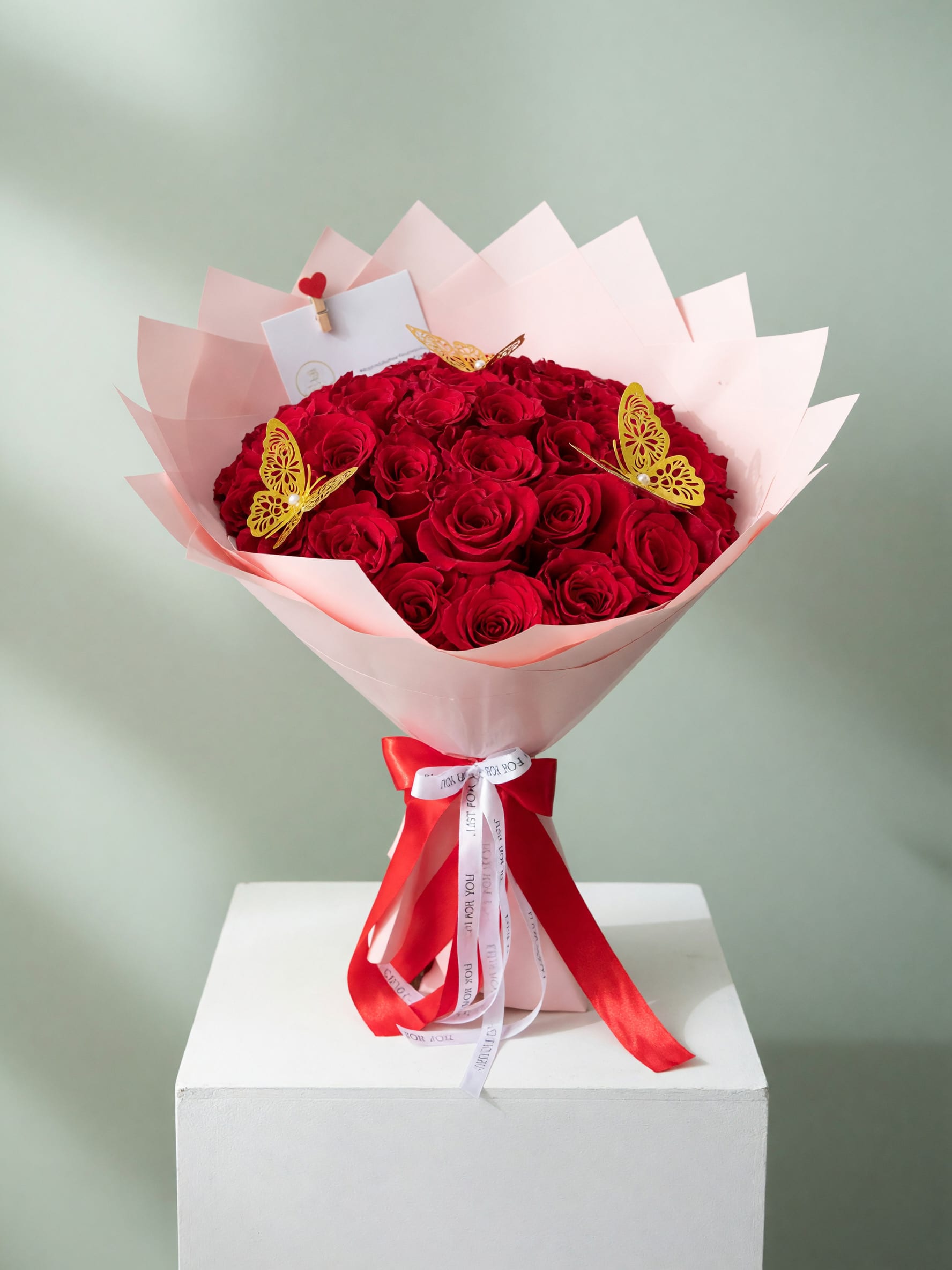 Bouquet of red roses wrapped in pink paper with a red ribbon