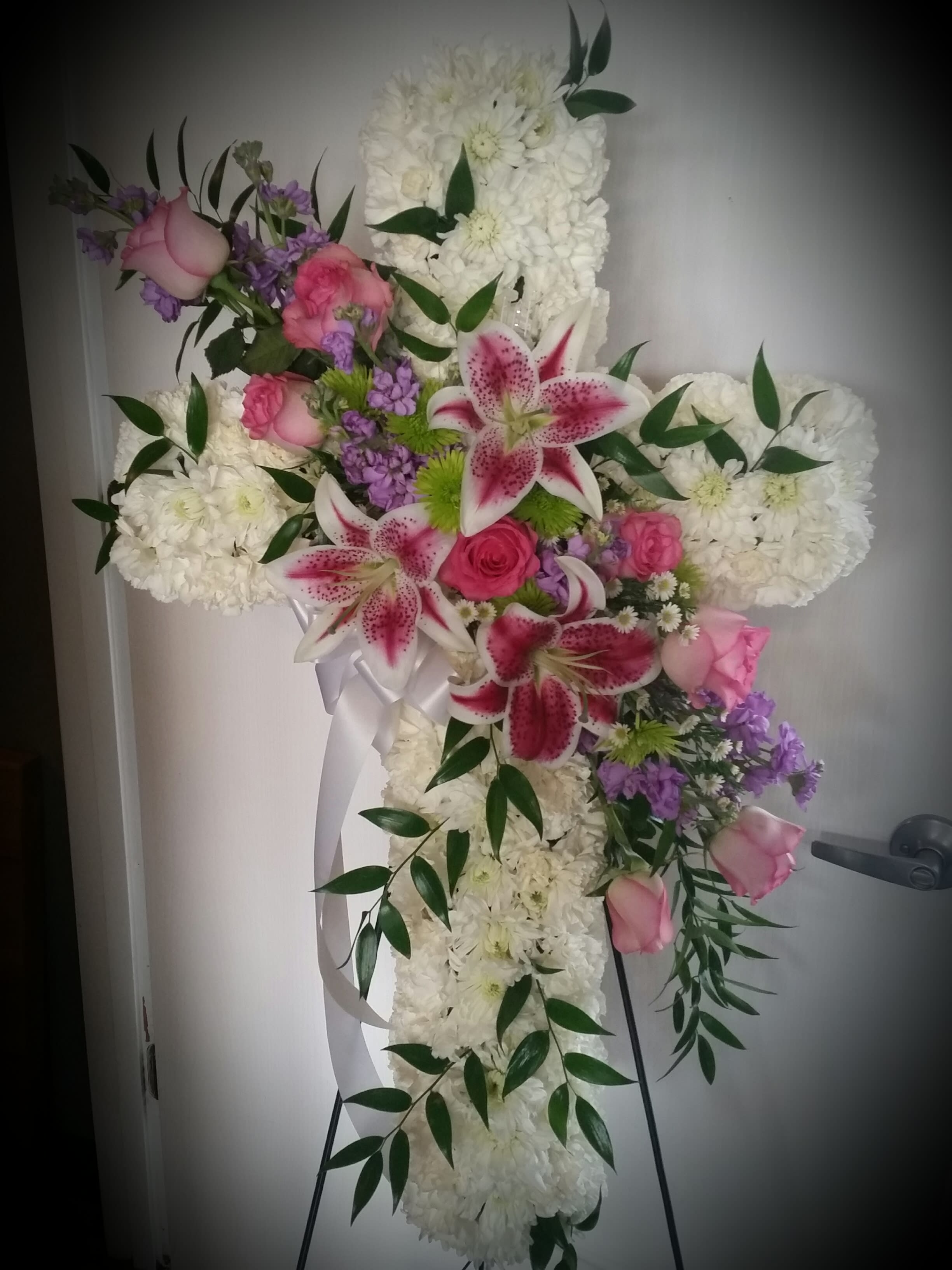 Cross-shaped floral spray with white blooms, pink roses, and lilies