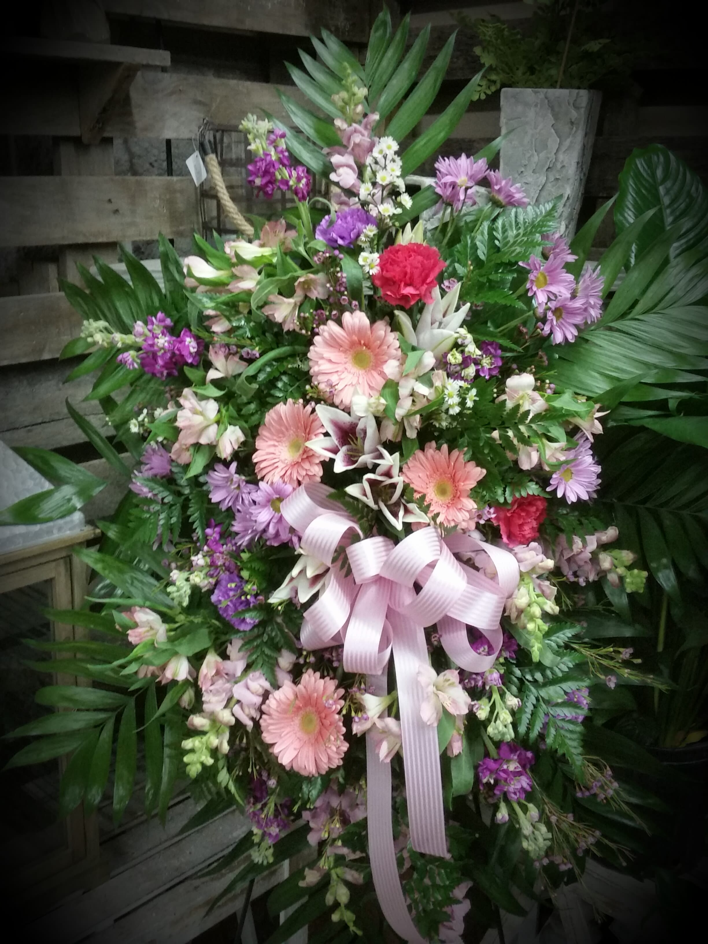 Large pink and purple floral standing spray with a ribbon bow