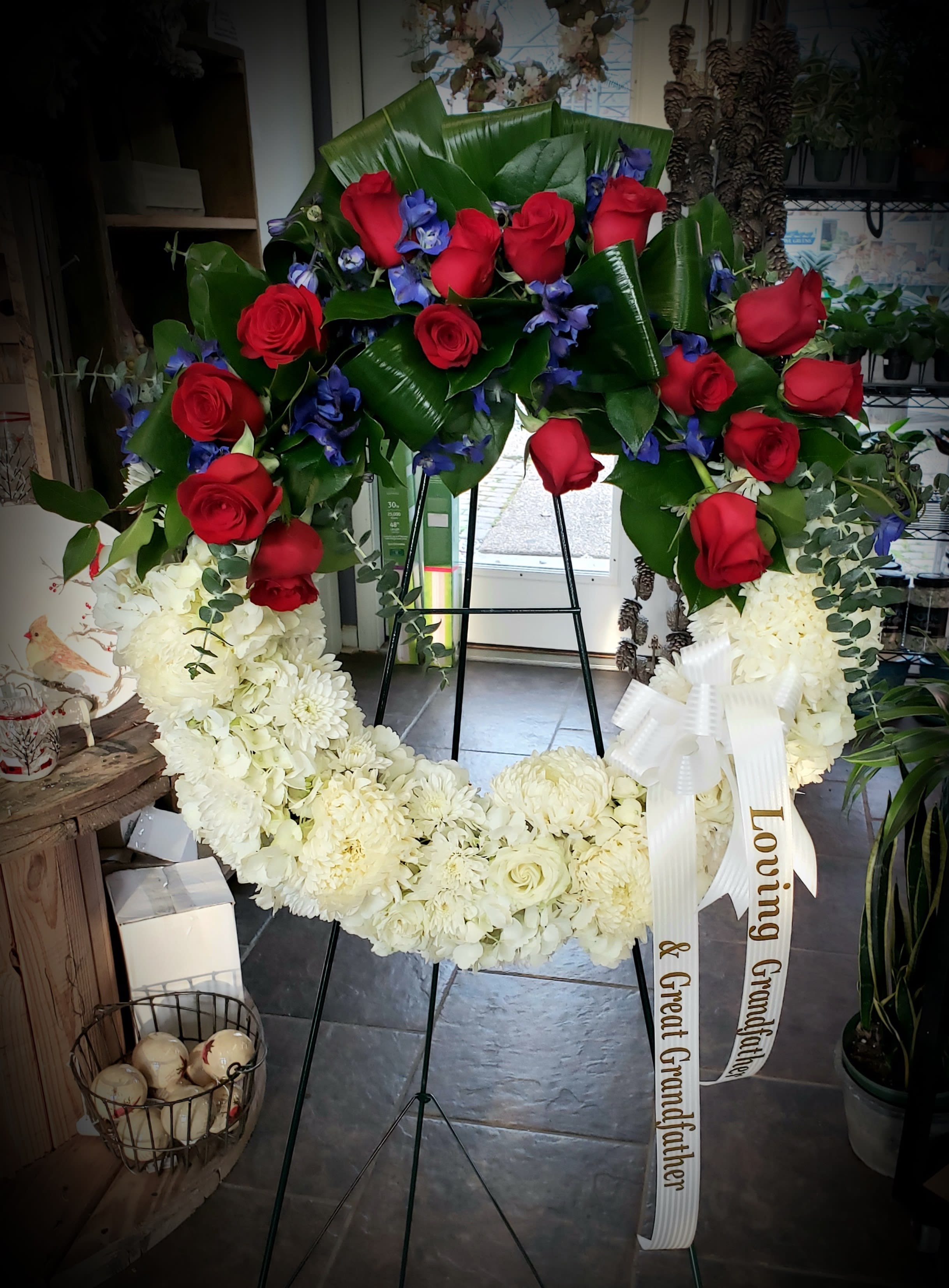 Large standing wreath of red roses and white flowers with a ribbon
