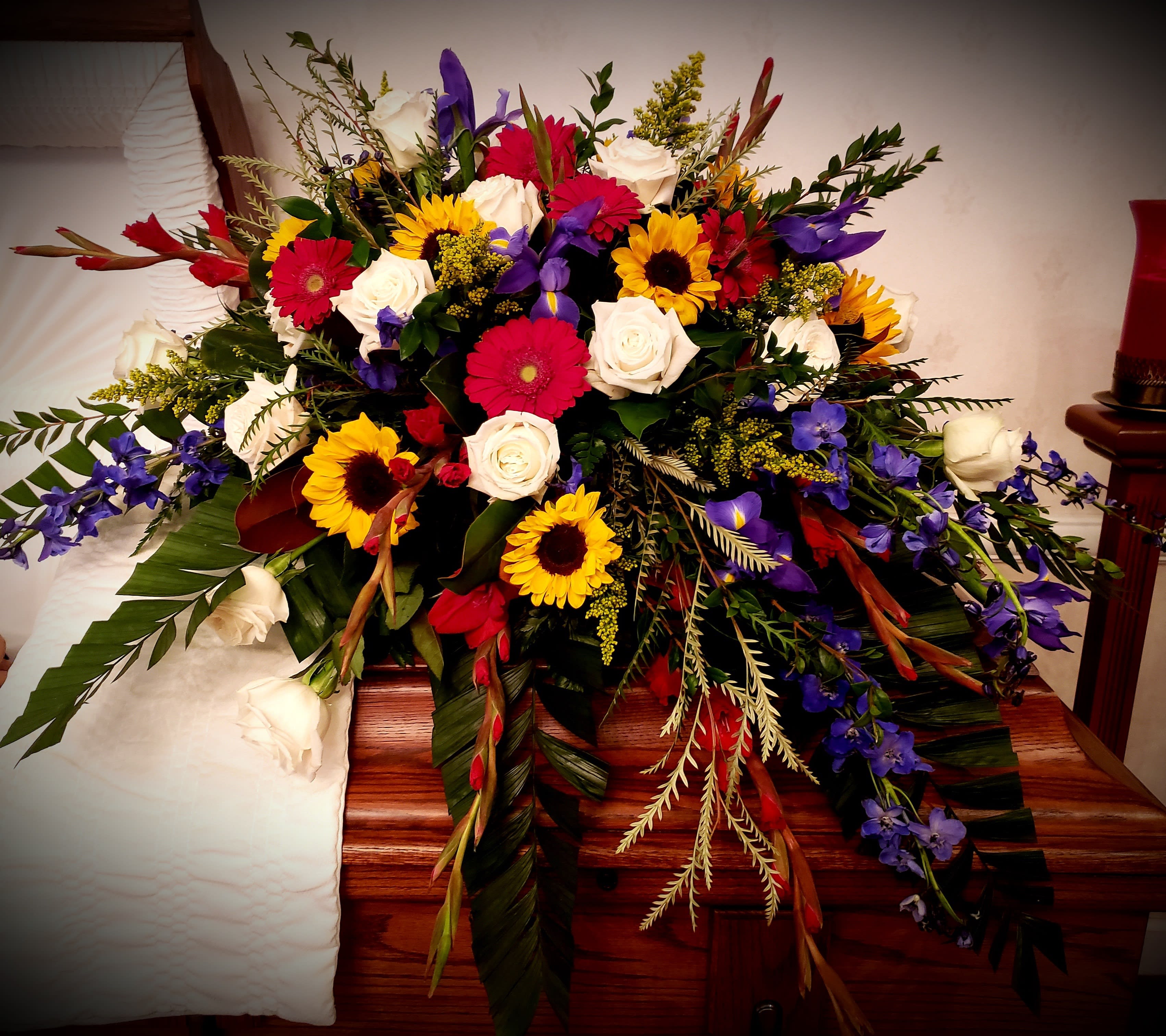 Large mixed floral spray with roses, sunflowers, and purple blooms