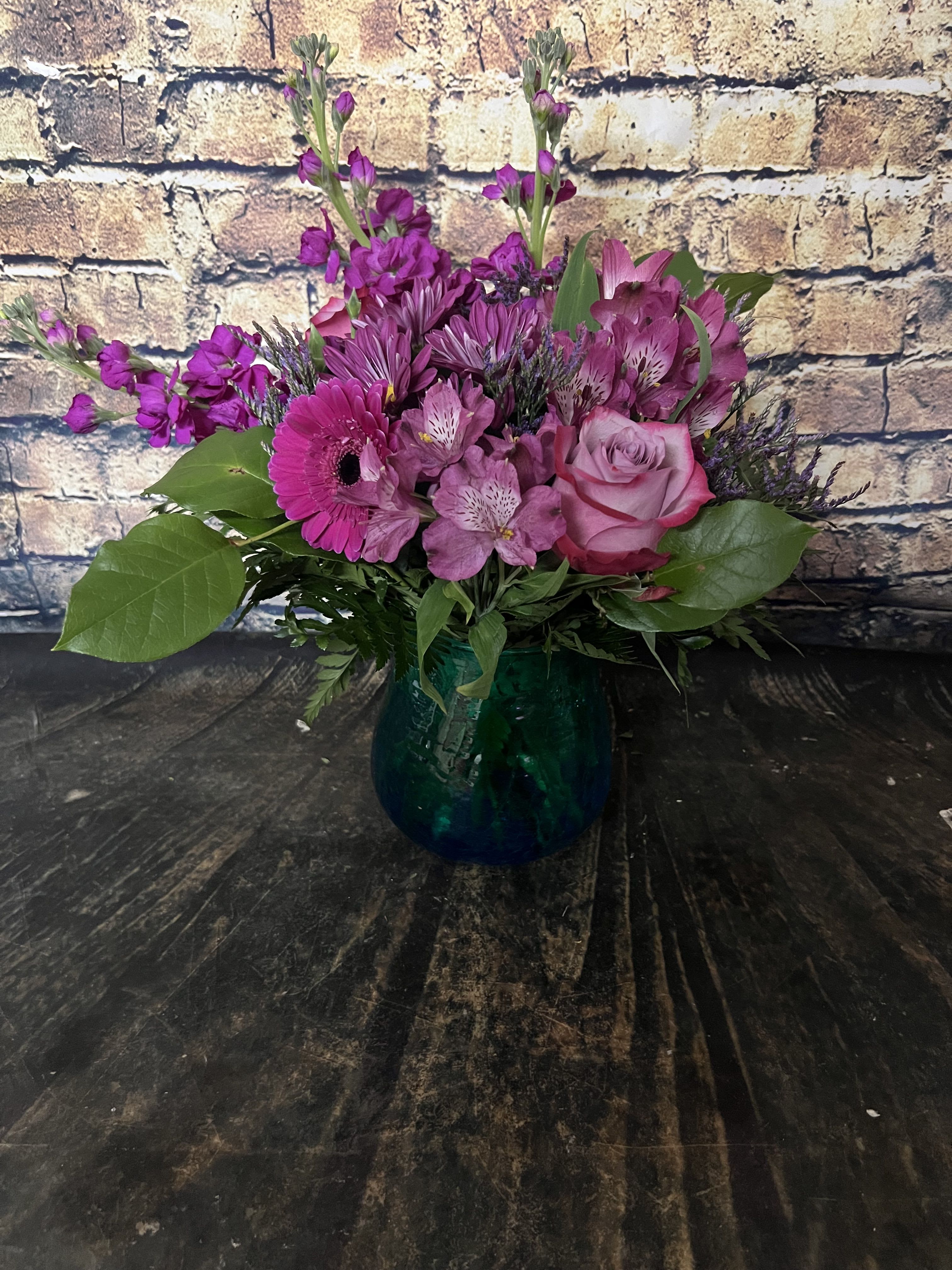 Deep Purple and Blue Hues Bouquet   - Vibrant colors of purple and fuchsia shine brightly out of the Blue Hues Vase.  Gerbers, stock and Deep purple roses and more are a unique mix to stand out from the crowd! 