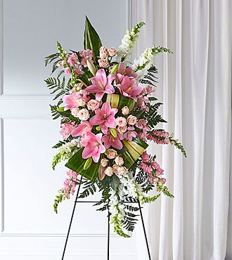 S5269S - Our Elegant Embrace Standing Spray shares the warmth and comfort your loved ones need during this difficult time through each blushing bloom. This spray beautifully combines lilies, spray roses and snapdragons with greens to express your heartfelt love.