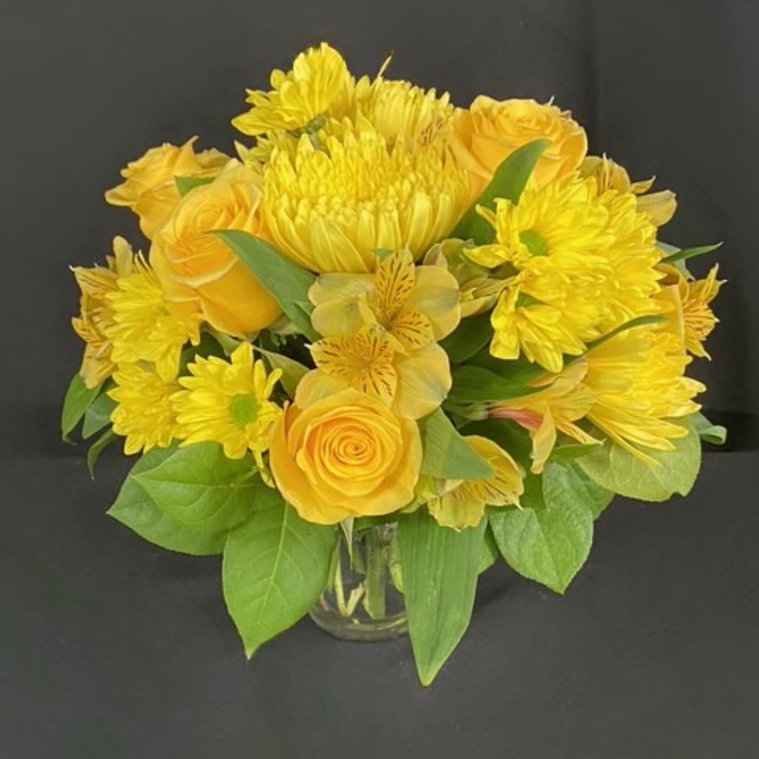 Yellow bouquet of roses and chrysanthemums in a clear glass vase