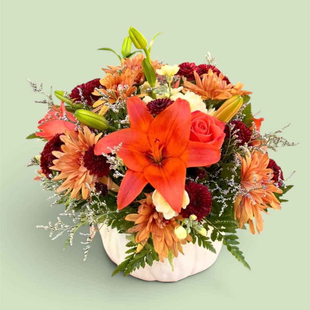 Orange lily and mixed autumn flowers in a white pumpkin vase