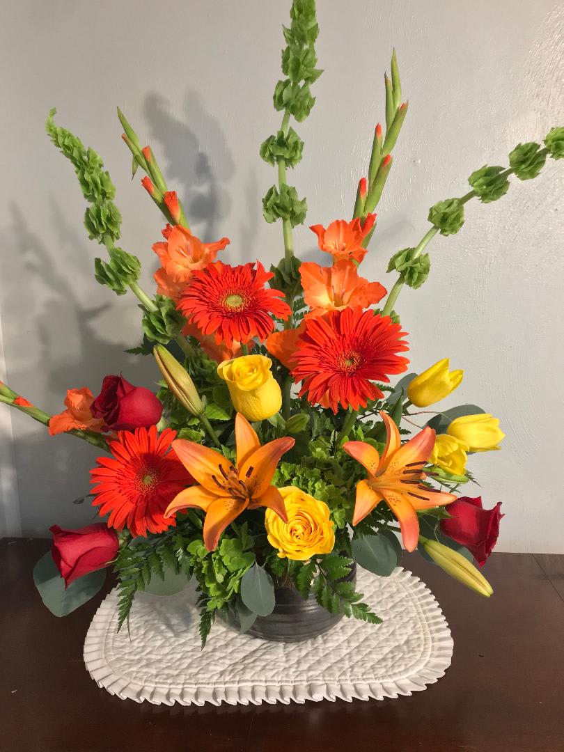 Mixed bouquet with red and yellow roses, orange lilies, and gerbera daisies in a vase