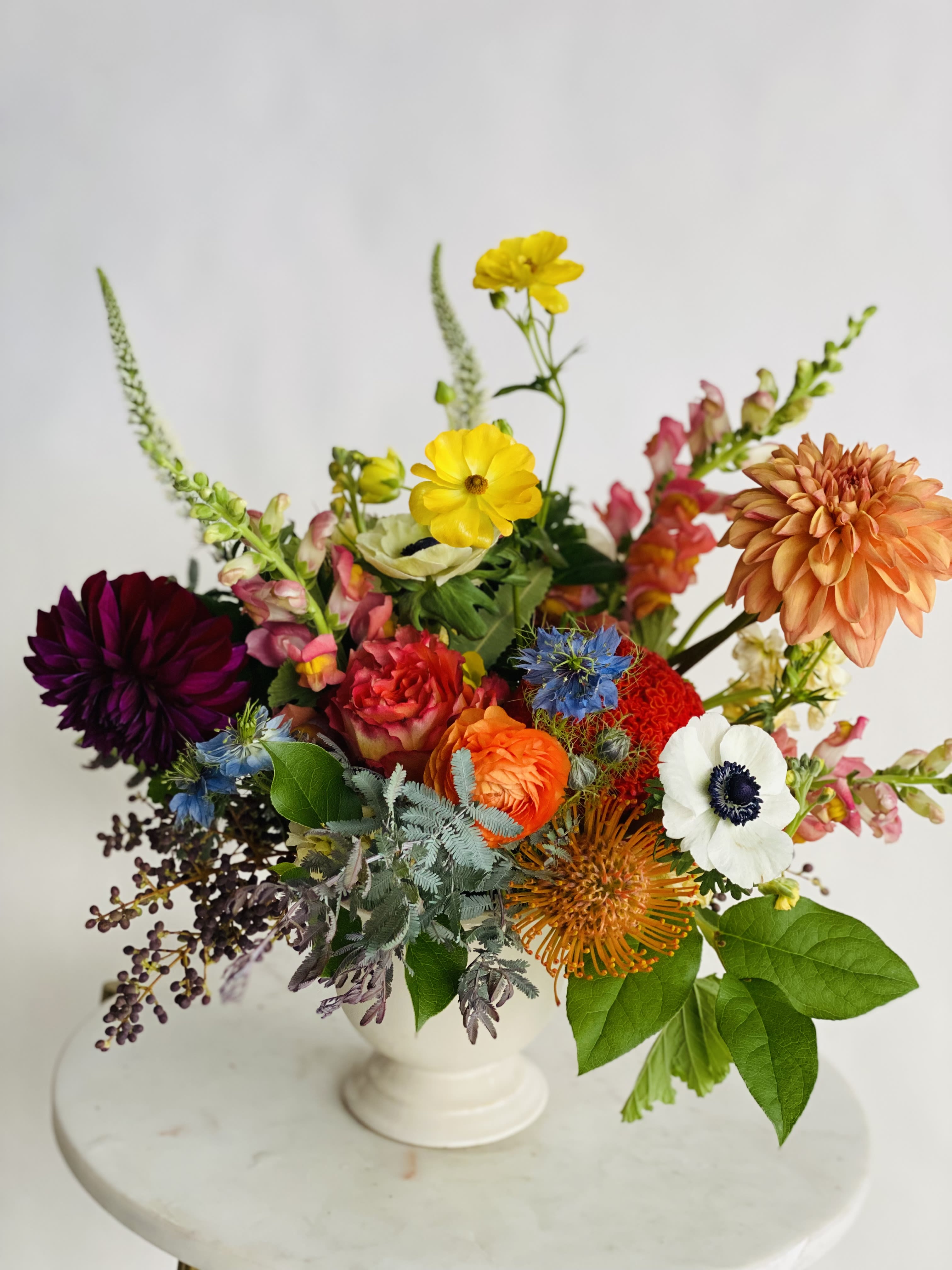 Colorful mixed flower arrangement in a white pedestal vase
