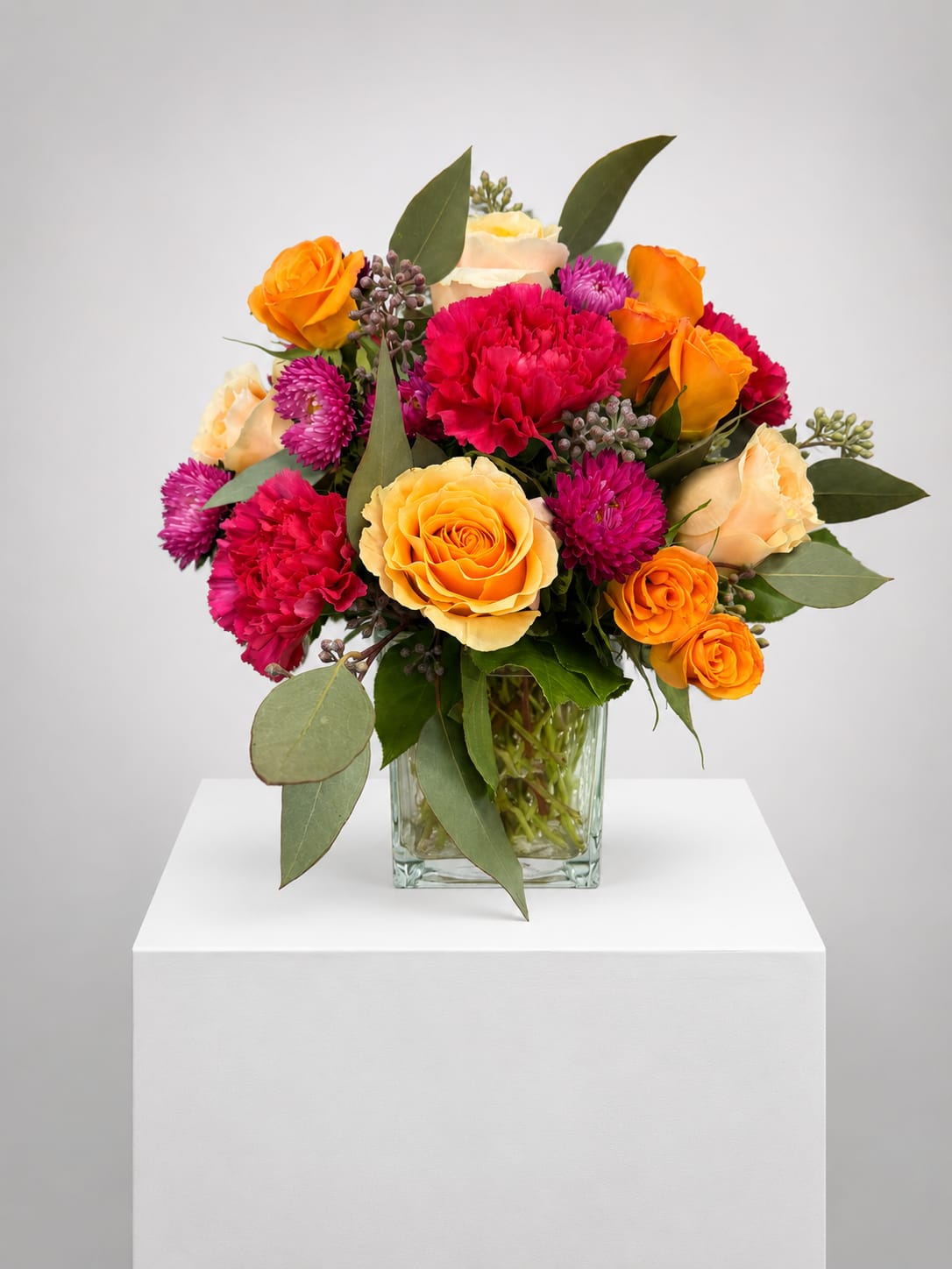 Mixed bouquet of orange and pink flowers in a glass vase