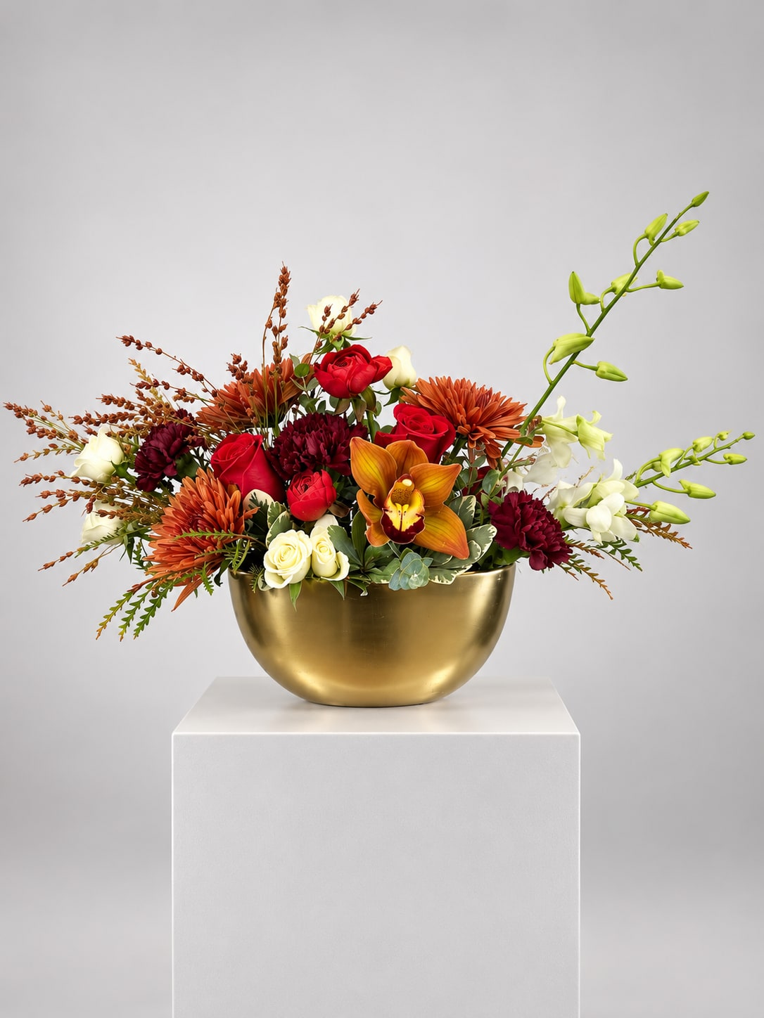 Mixed bouquet in a gold bowl with red, white, and orange flowers