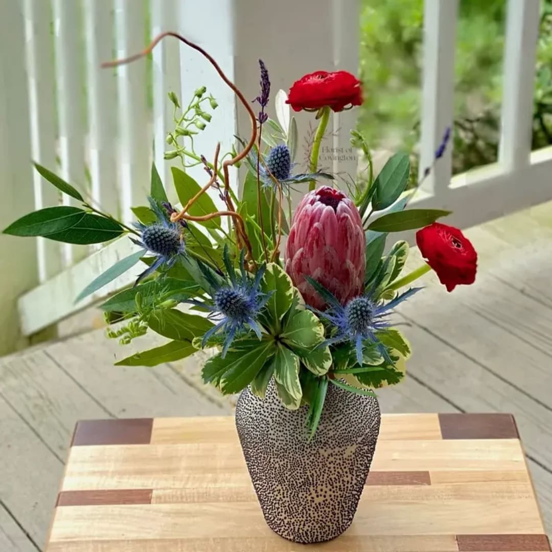 Mixed floral arrangement in a speckled vase with red and blue blooms