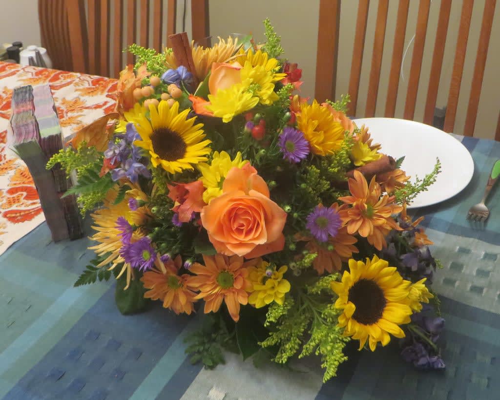 Mixed bouquet with sunflowers, orange roses, and purple flowers on a table