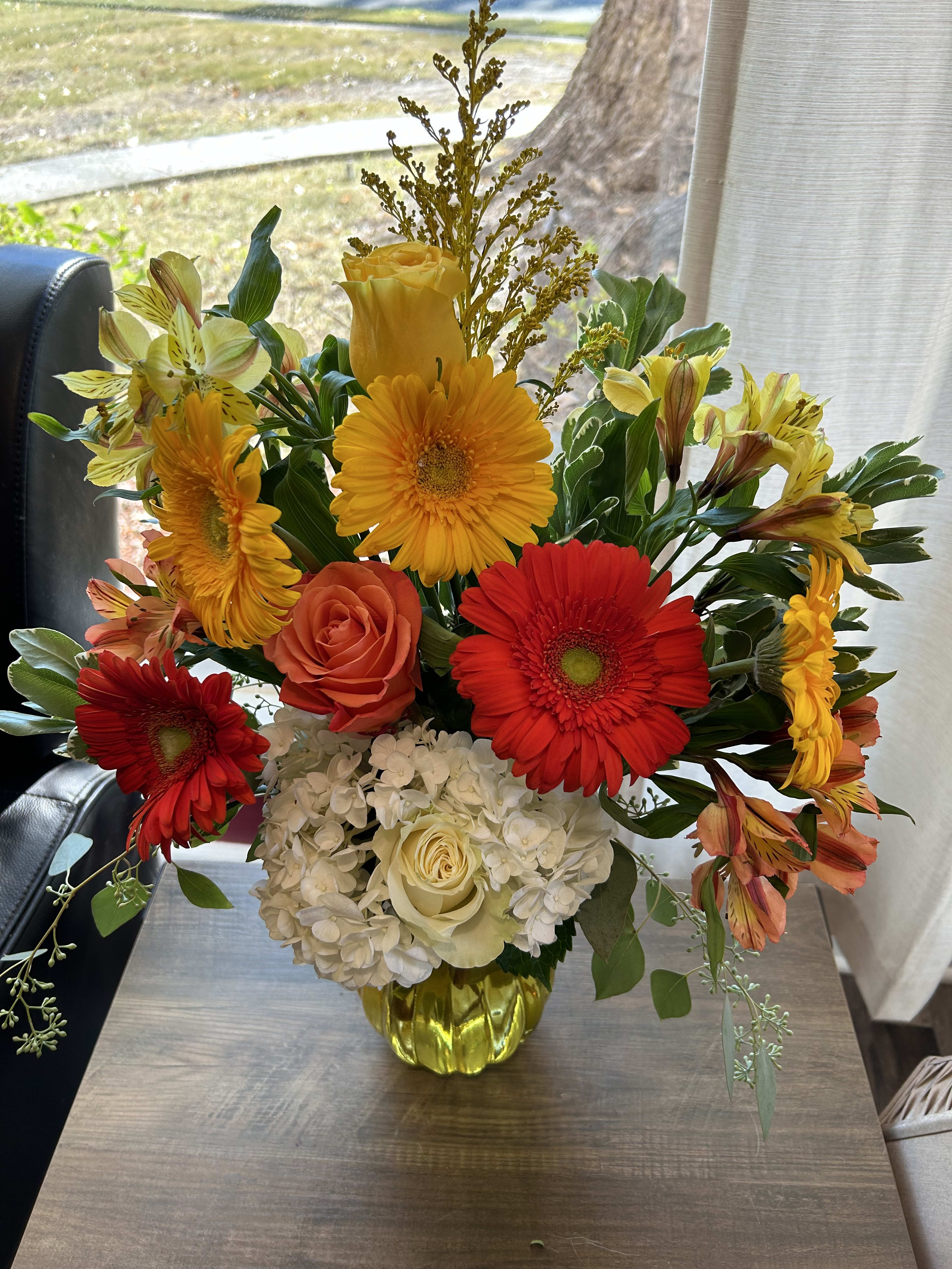 Bright mixed bouquet in a yellow vase with red, orange, and white flowers