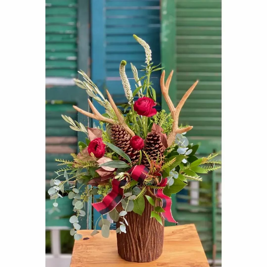 Red roses in a brown vase with pinecones and antler accents
