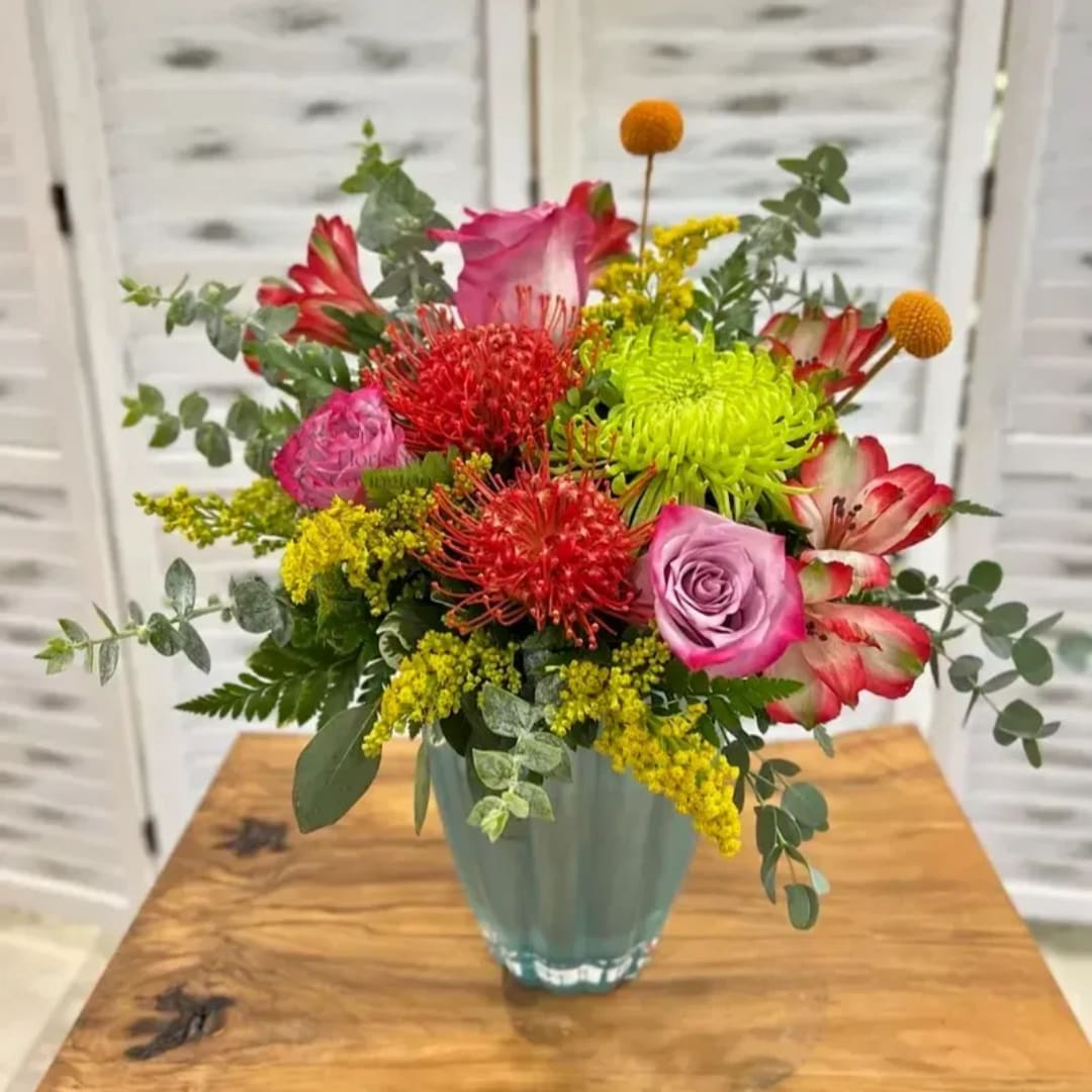 Mixed bouquet of pink, red, and yellow flowers in a glass vase