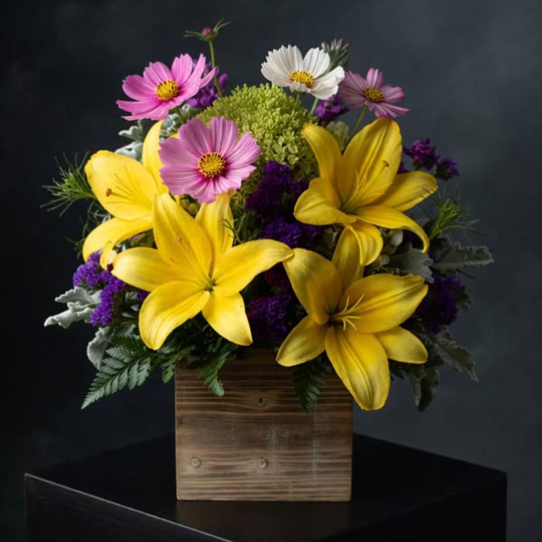 Yellow lilies and pink daisy-like flowers in a wooden box