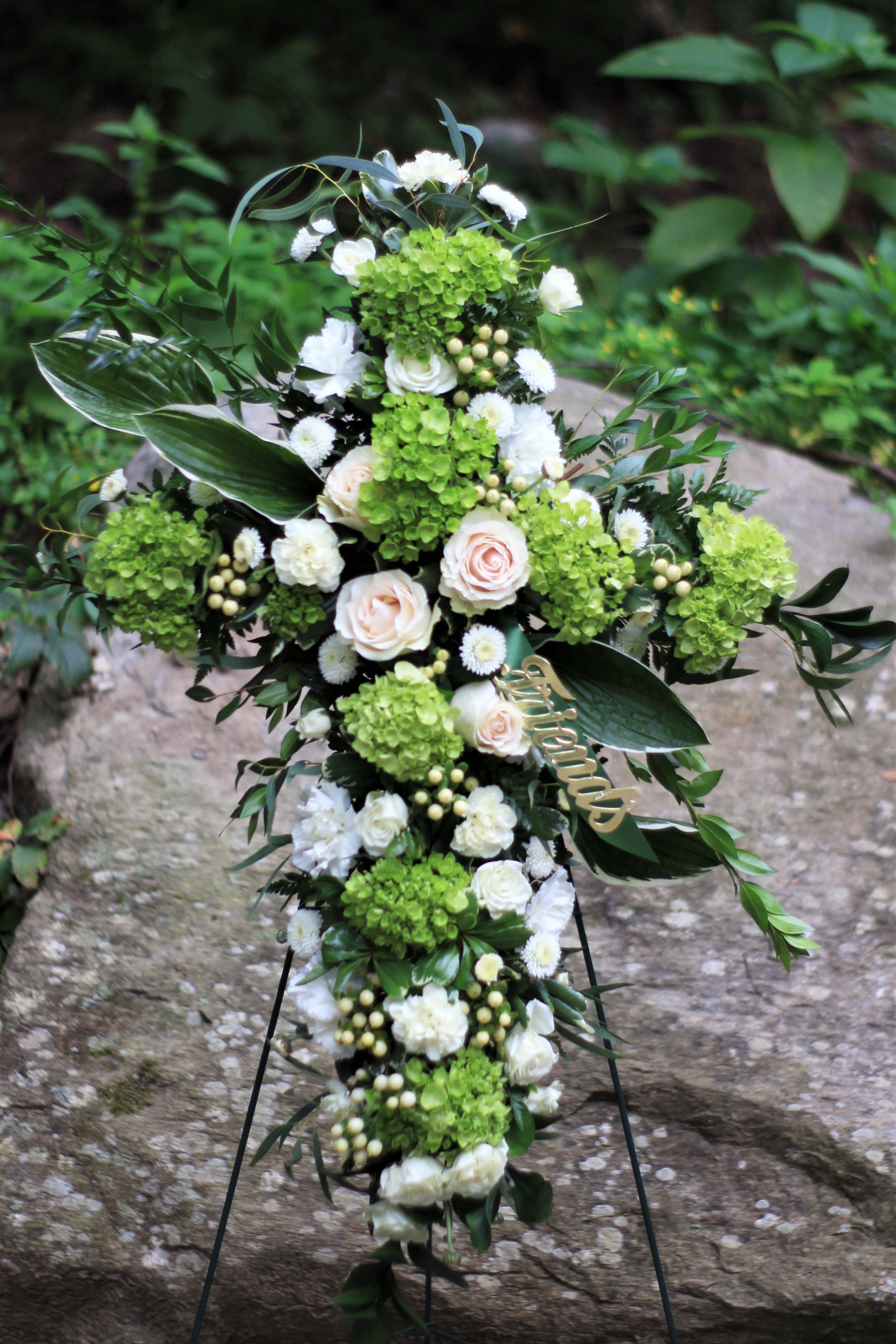 Cross-shaped floral funeral spray with white and green flowers