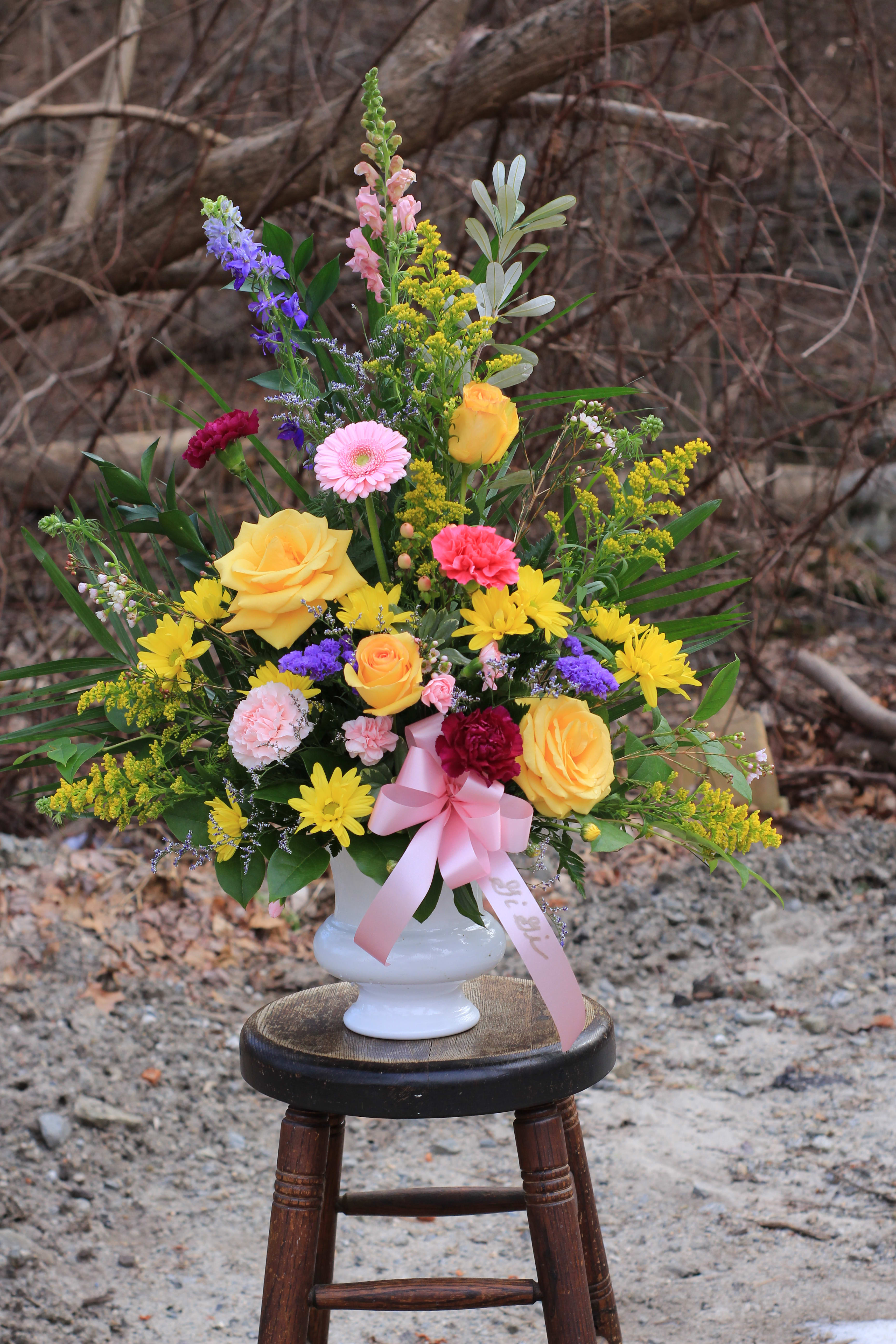 Colorful mixed bouquet in a white vase with a pink ribbon