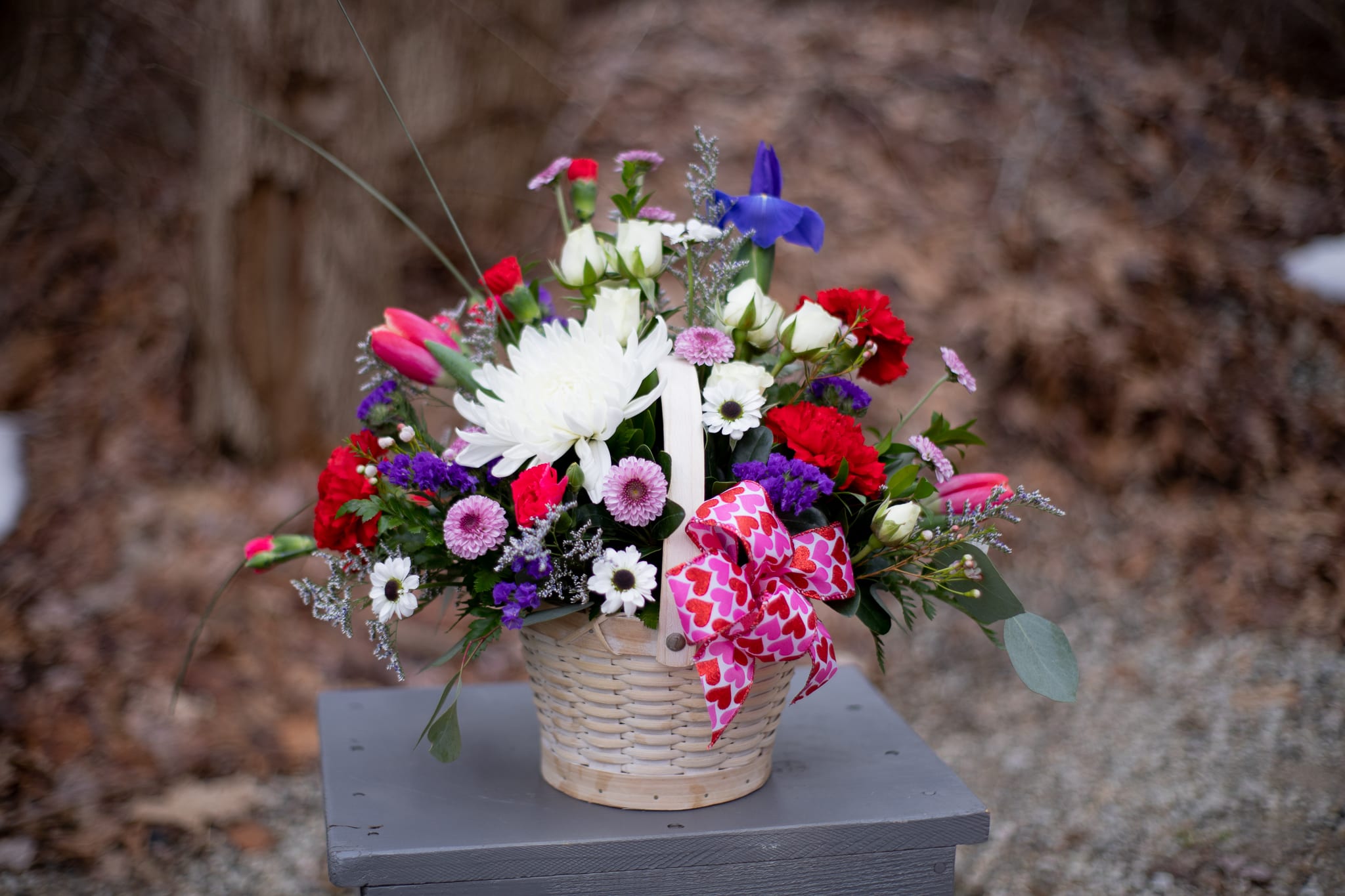 Mixed bouquet in a wicker basket with a pink heart ribbon