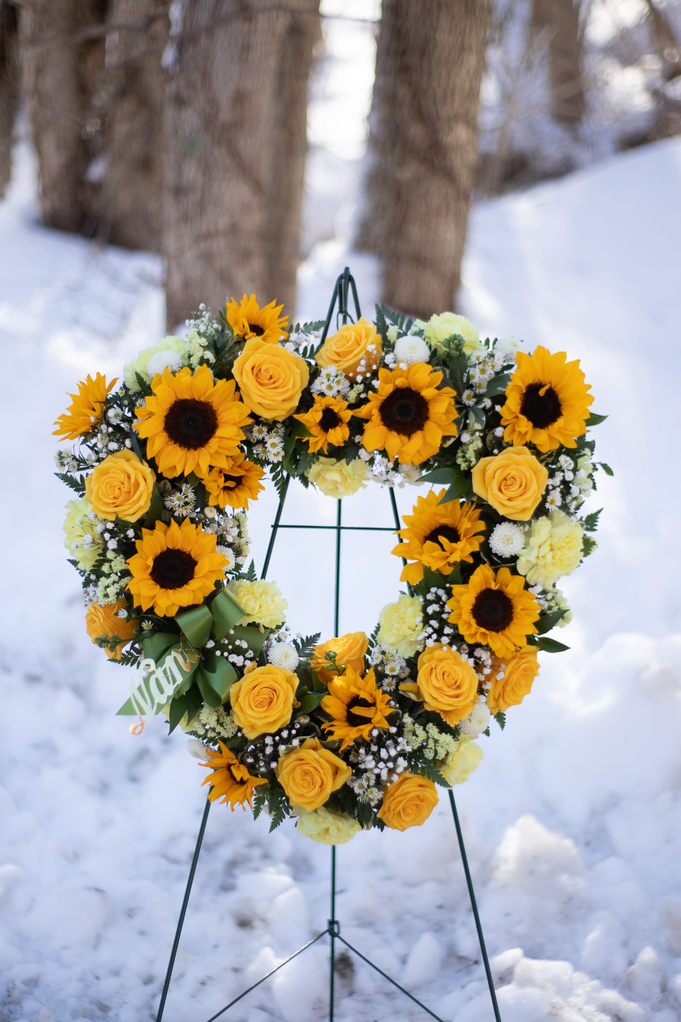 Heart-shaped wreath of yellow roses and sunflowers on a stand