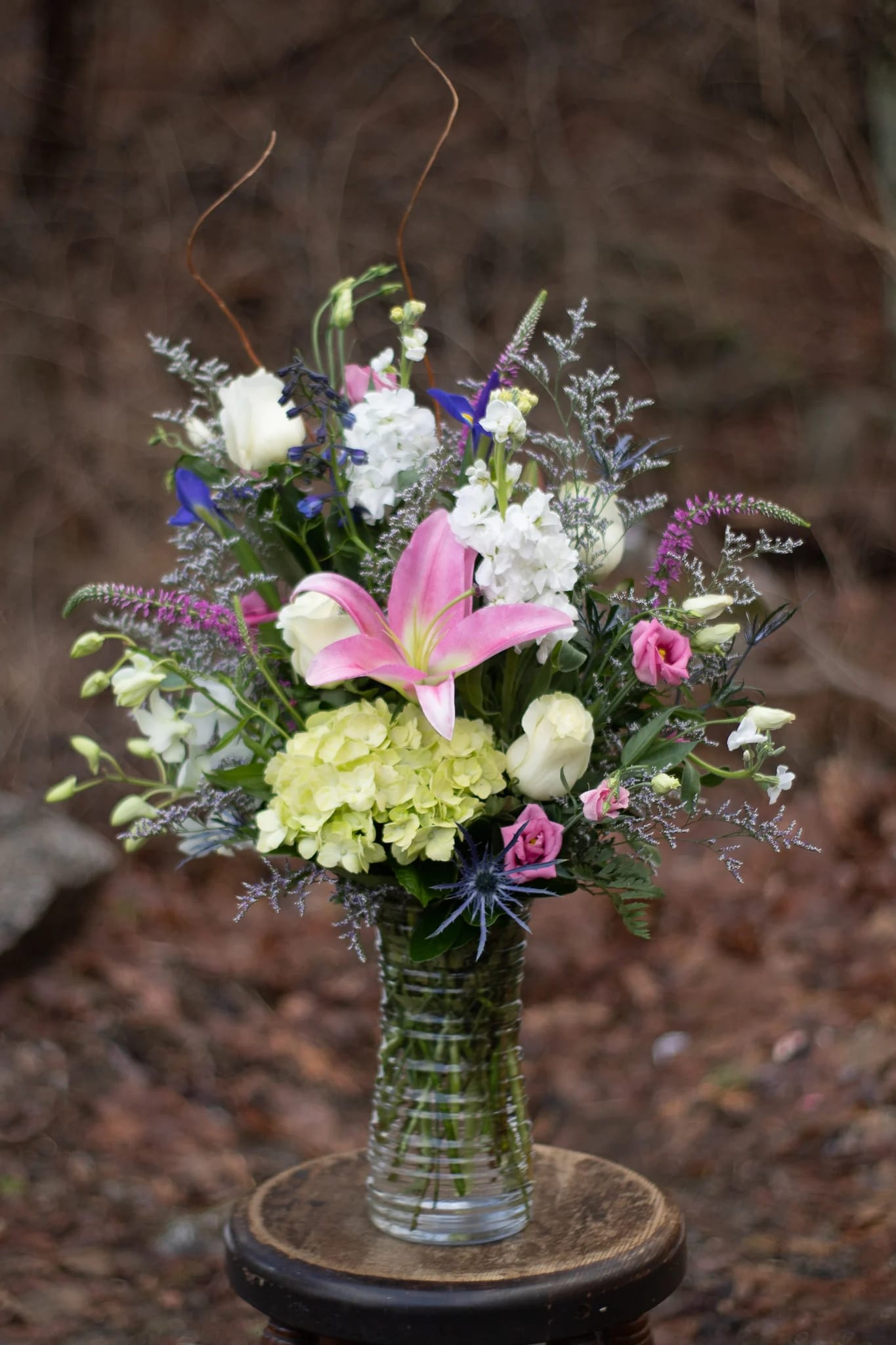 Mixed bouquet in a clear glass vase with pink lily and white blooms