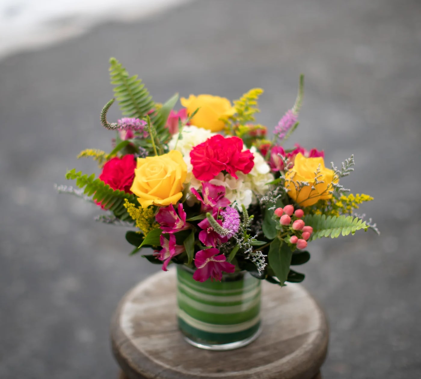 Colorful bouquet of roses and mixed flowers in a striped glass vase