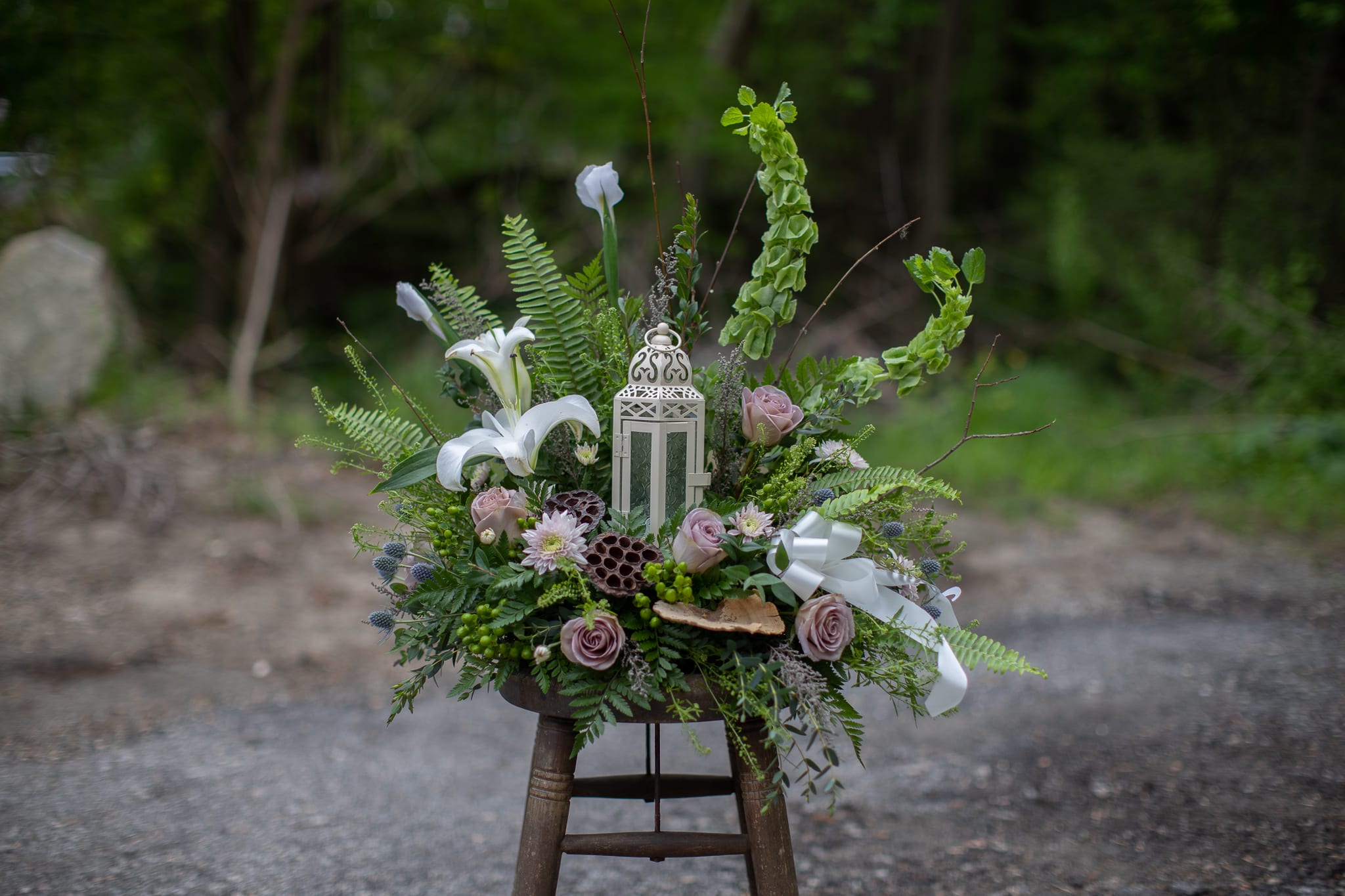 Floral arrangement with white lilies, lavender roses, and a lantern centerpiece
