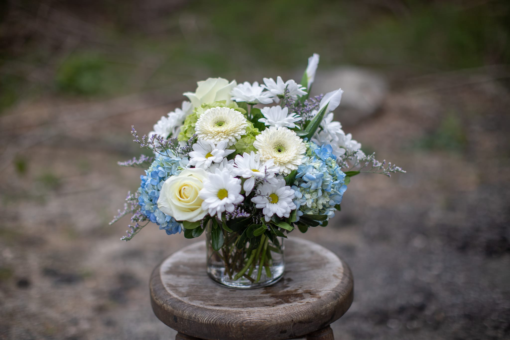 White and blue flower arrangement in a clear glass vase
