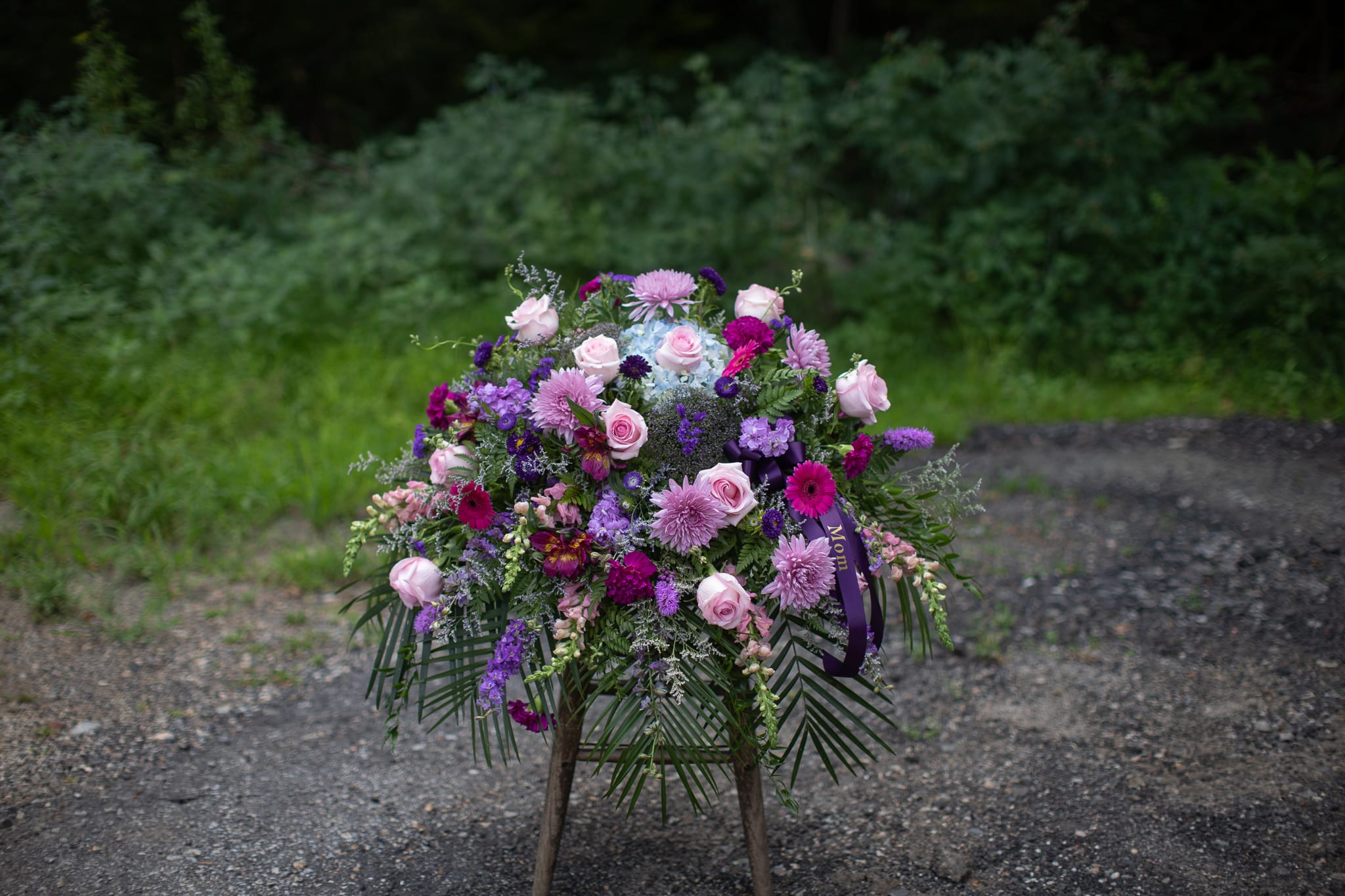 Standing floral spray with pink and purple blooms on a wooden easel