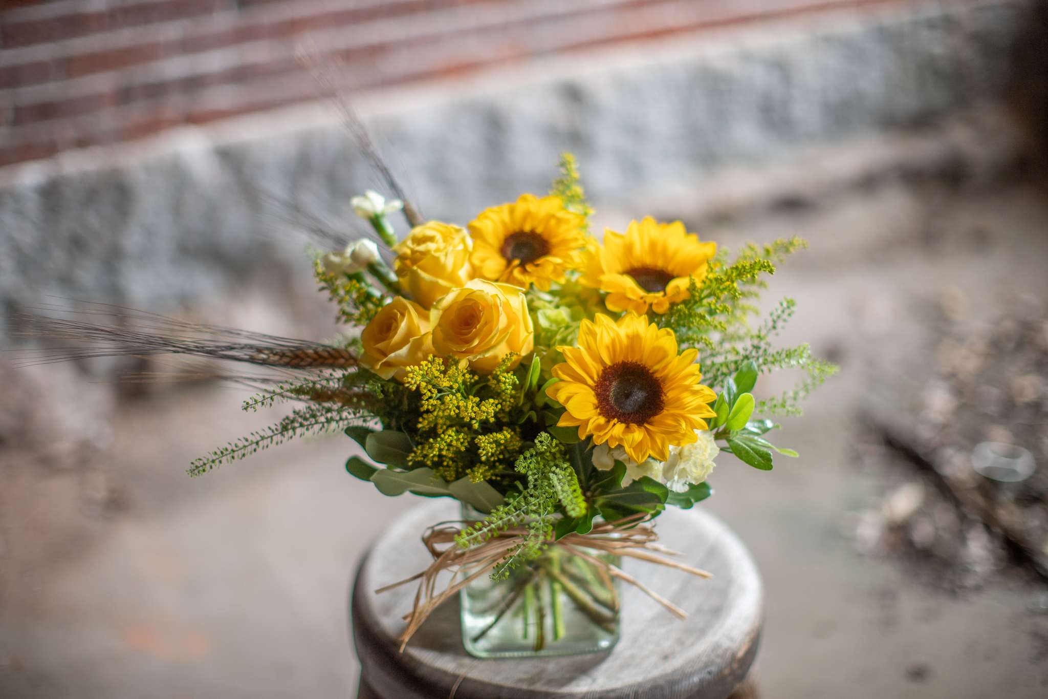 Yellow sunflowers and roses in a square glass vase