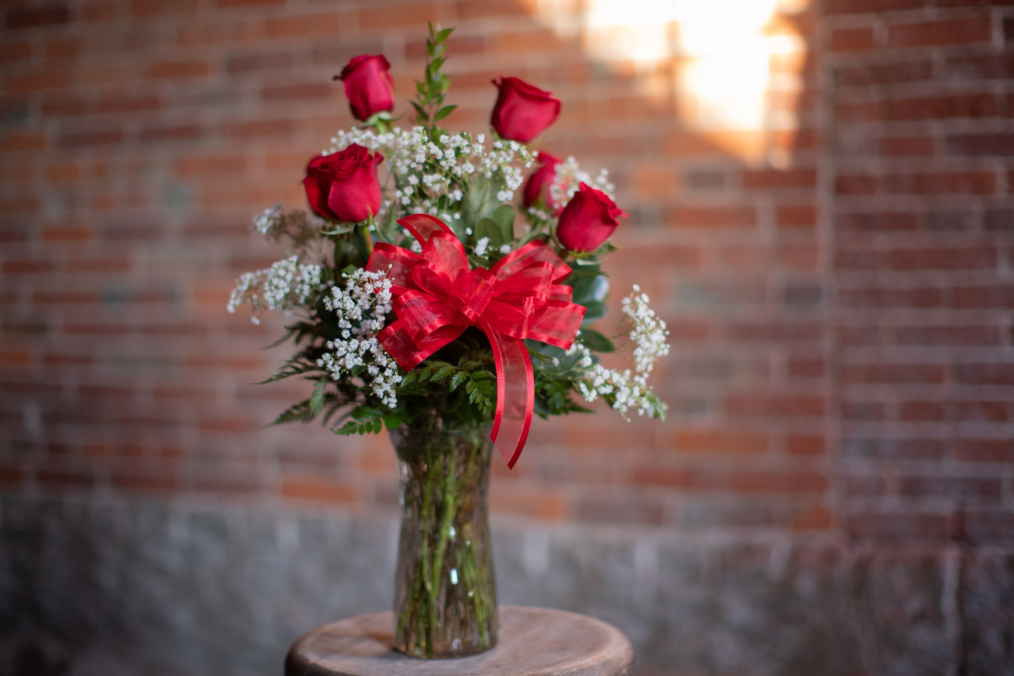 Bouquet of red roses and baby's breath in a glass vase with a red bow