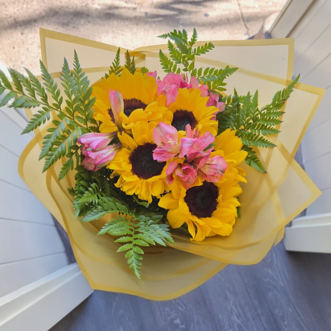Bouquet of yellow sunflowers and pink alstroemeria wrapped in yellow paper