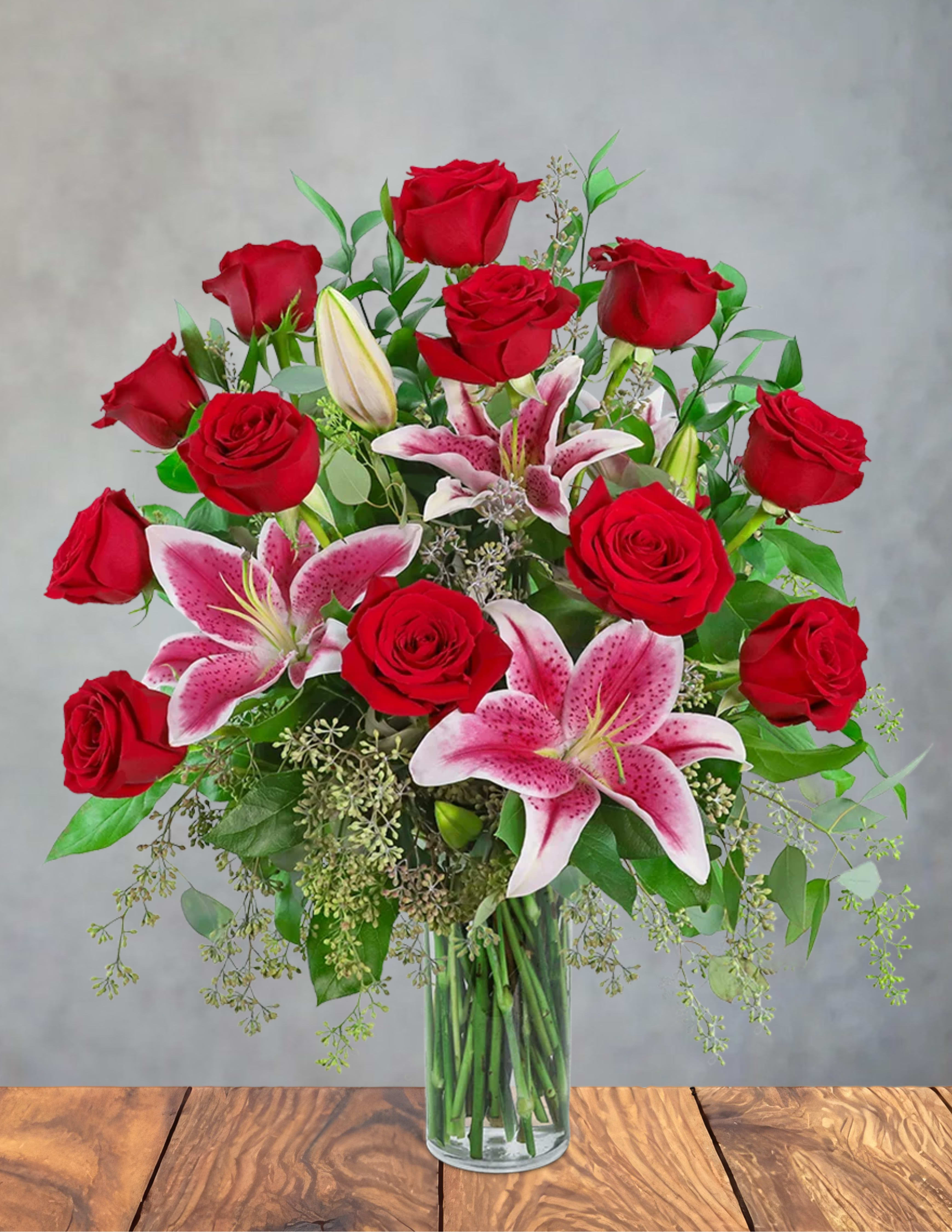 Red roses and pink lilies in a clear glass vase