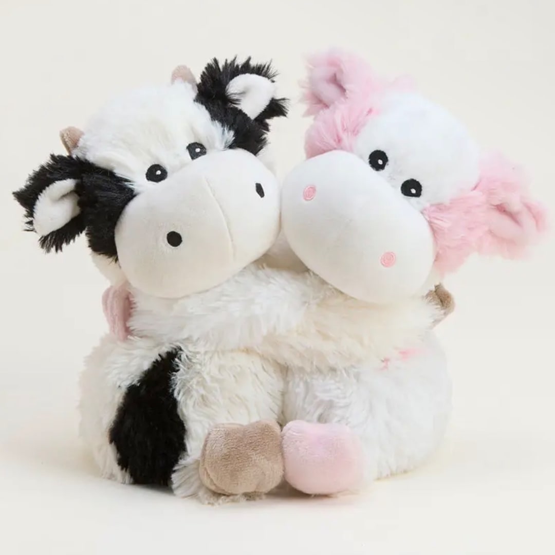Two plush cow toys, one black-and-white and one pink-and-white, sitting together