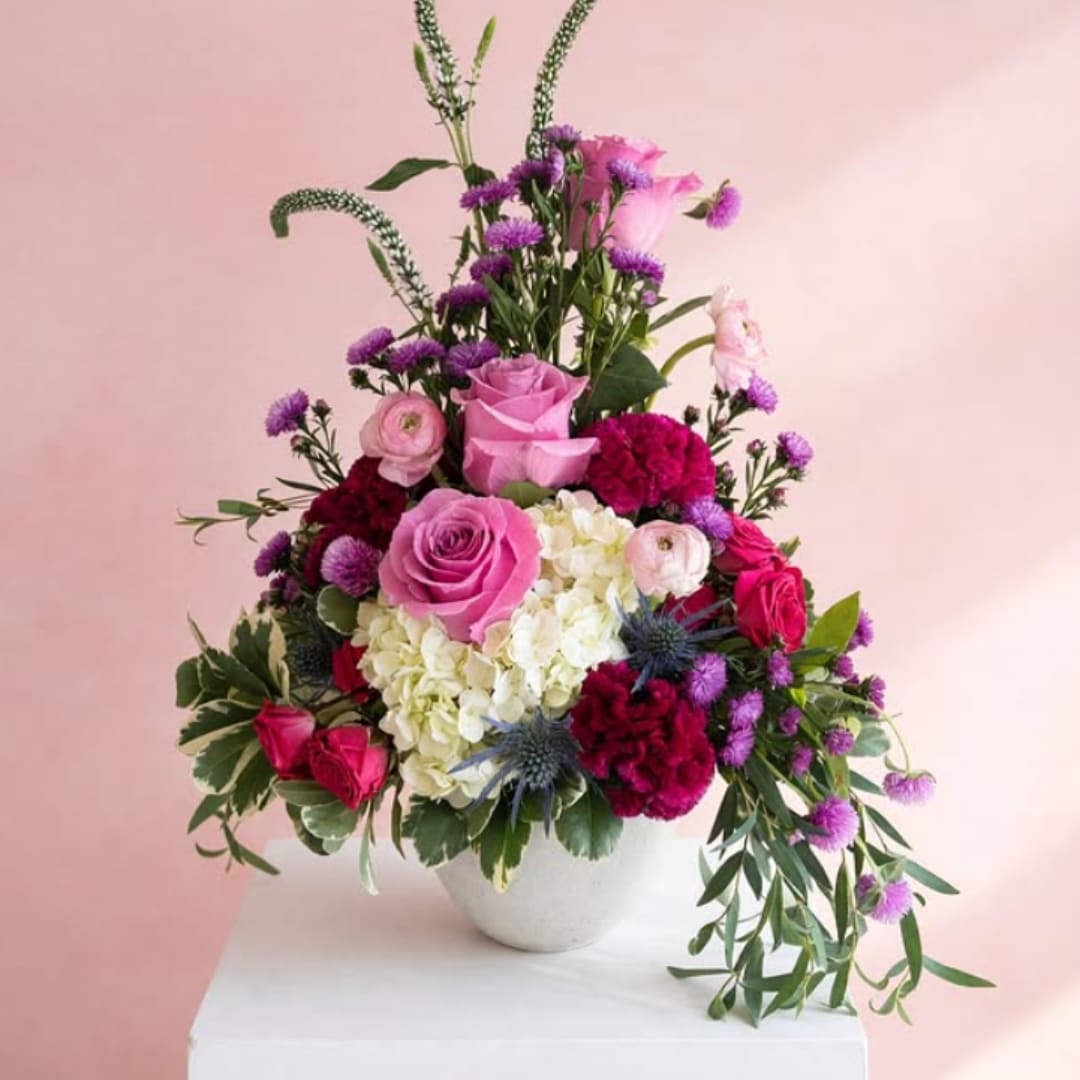 Pink and purple mixed flower arrangement in a white vase
