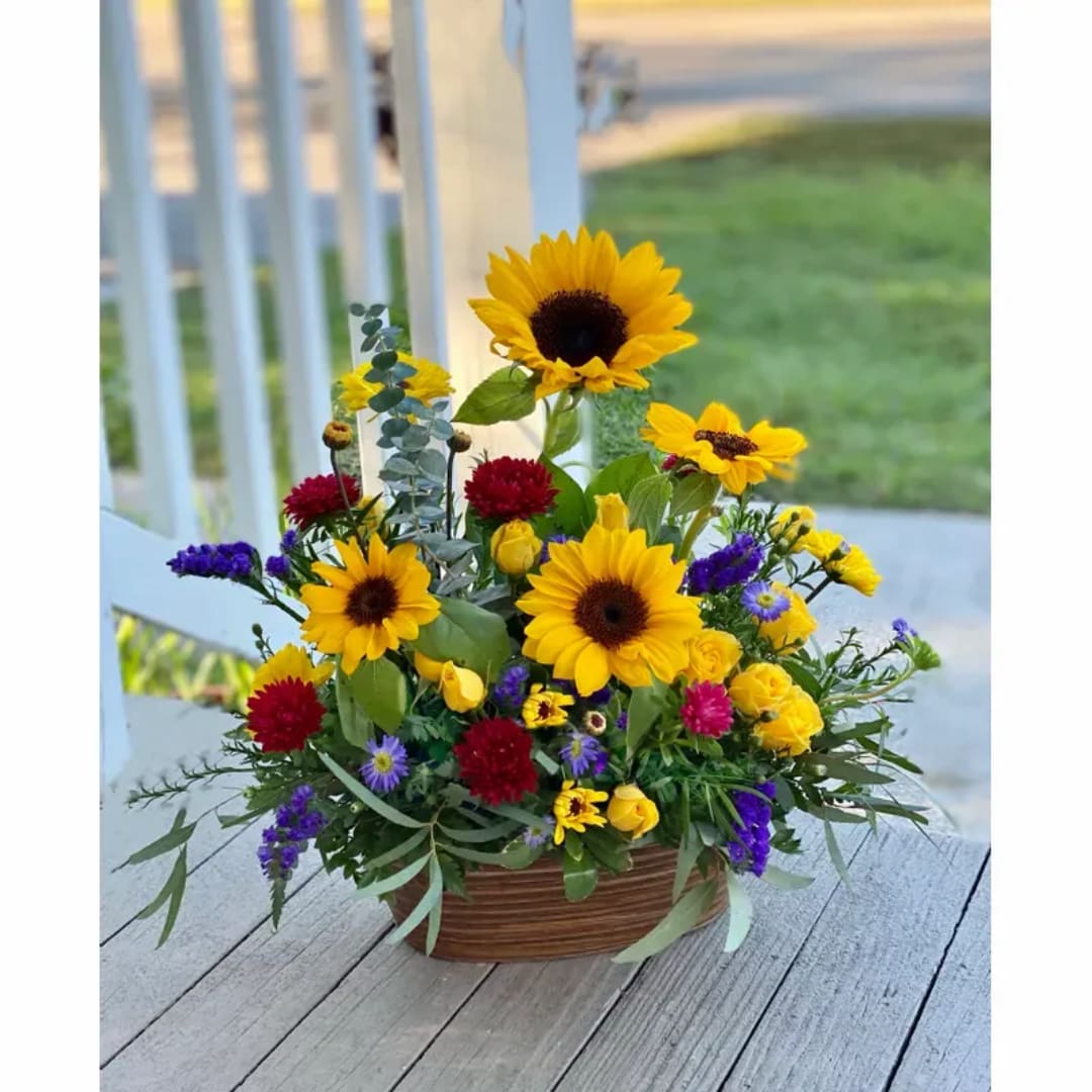 Mixed bouquet with sunflowers, yellow roses, and purple flowers in a basket