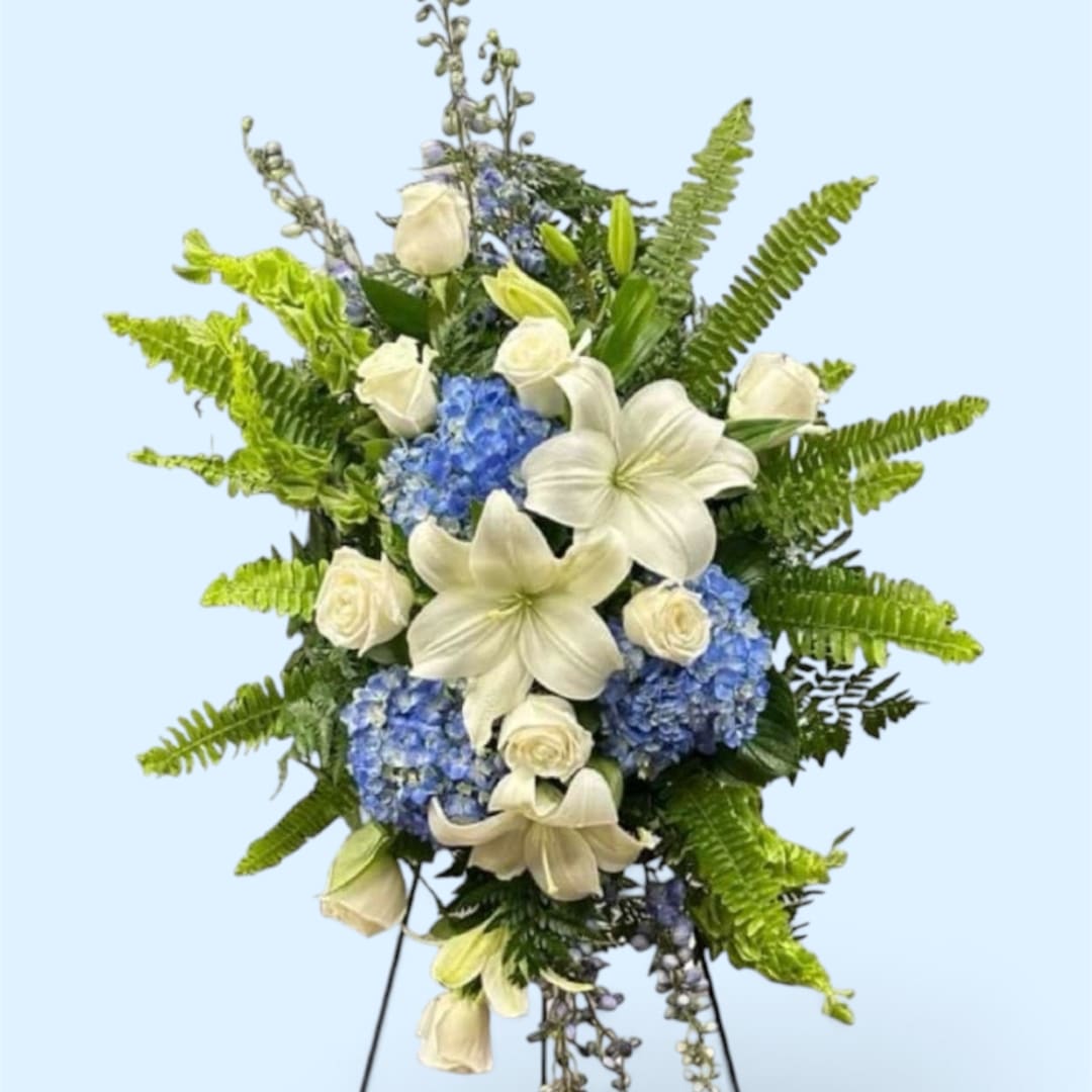 White lilies and roses with blue hydrangeas in a standing spray