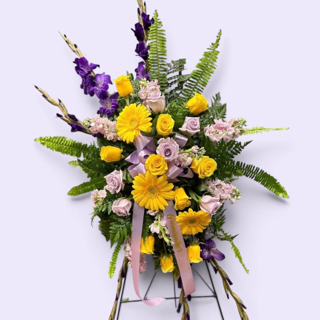 Yellow and lavender floral arrangement with ribbon on a stand