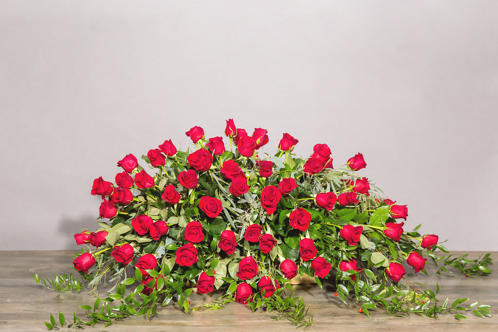 Large arrangement of red roses with trailing greenery on a table