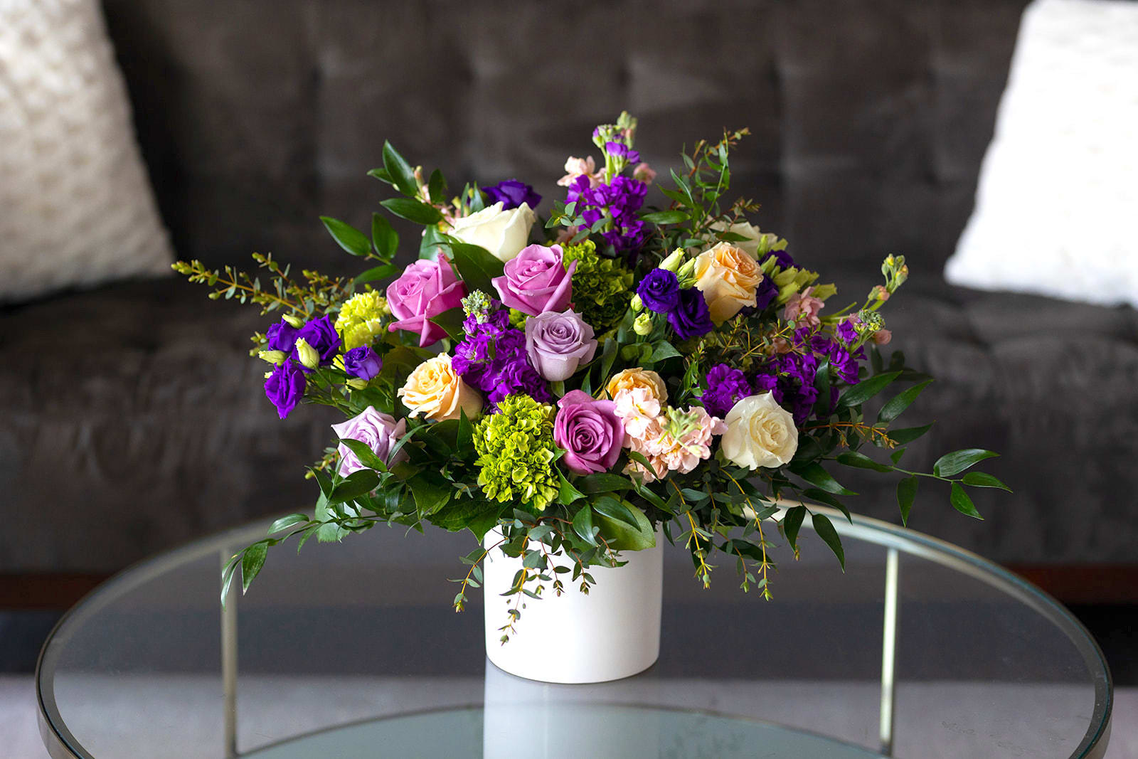 Mixed bouquet of roses and purple blooms in a white vase