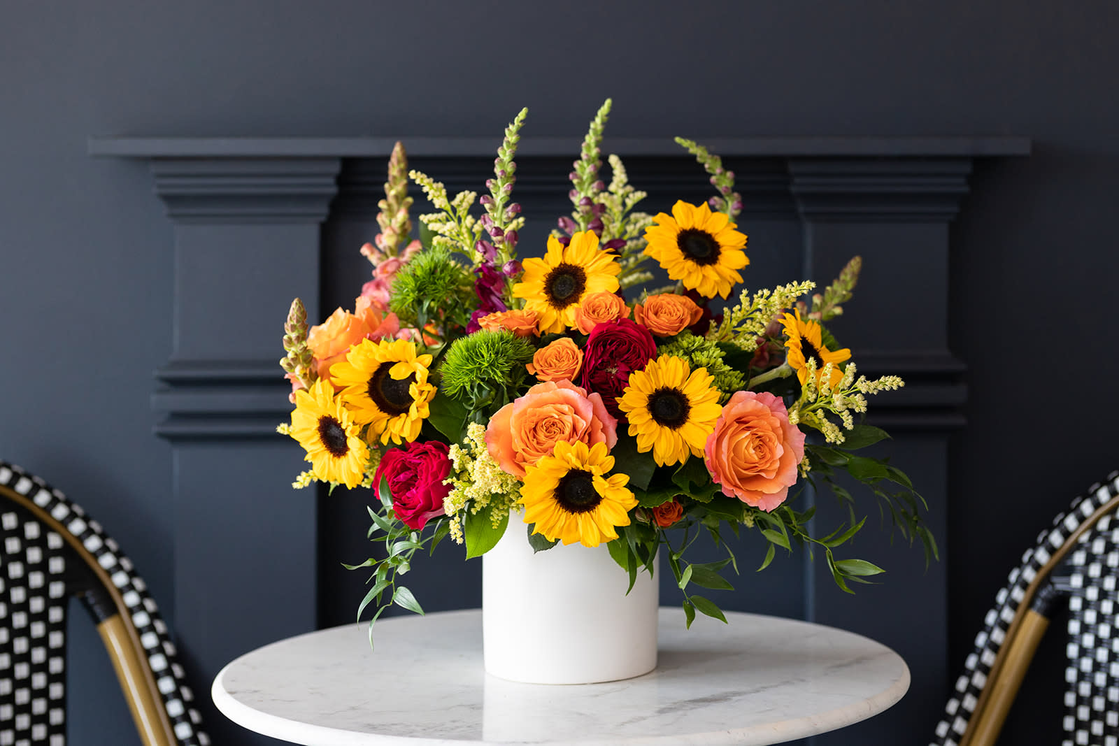 Bright mixed bouquet in a white vase with sunflowers and roses