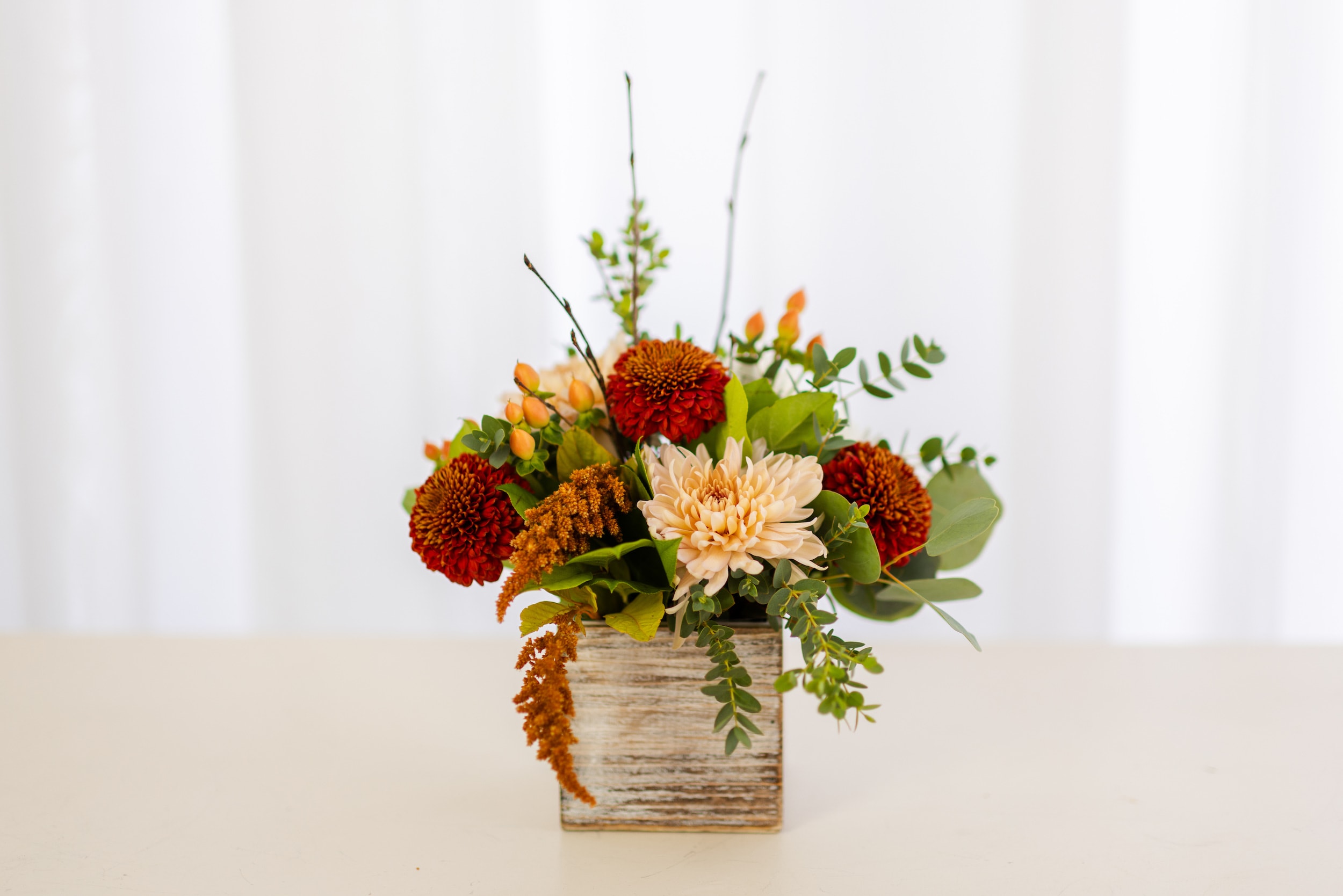 Chai Latte Collection - Small Wood Box - All the vibes of warm fall spices inspired our new Chai Latte Collection. Shades of cinnamon, mocha and cream come together through flowers like mums, roses, berries and branches - all designed in a white-washed wood box. An ideal gift for a friend or loved one, or the perfect addition to a fall feast. This design is perfect for a centerpiece, desk or accent table.   Product Details: The Chai Latte Collection Small Wood Box is 8" tall and 6" wide. The Premium size includes an additional 7 stems of flowers and greenery. 