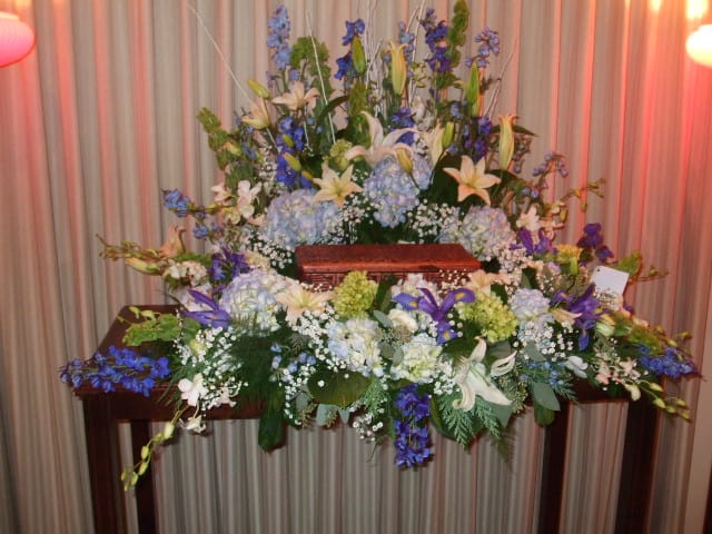 Large floral casket spray with white lilies and blue flowers
