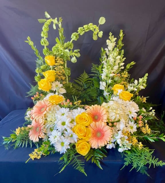 Floral arrangement with yellow roses, peach gerbera daisies, and white daisies