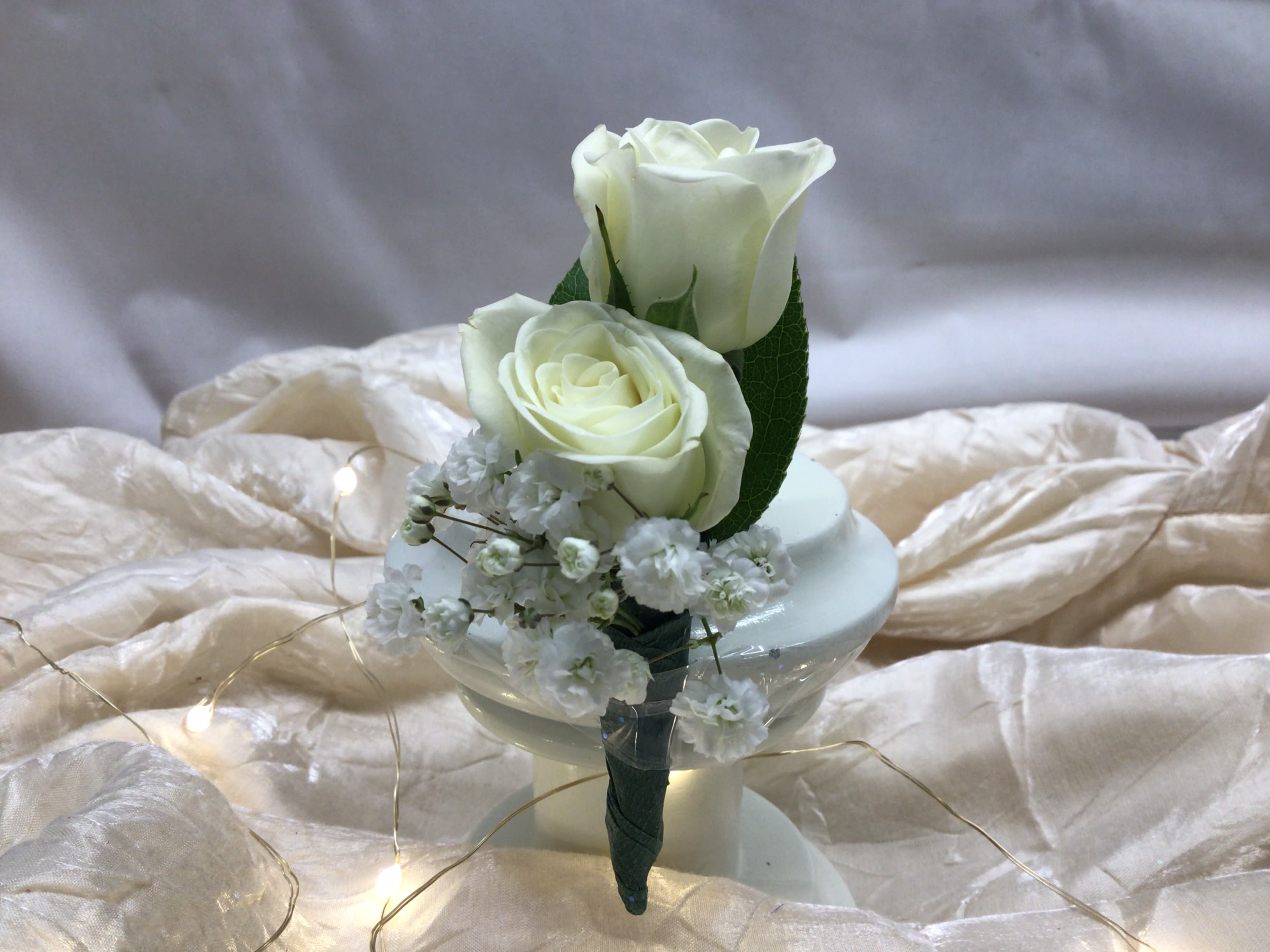 Two white roses with baby's breath in a small holder