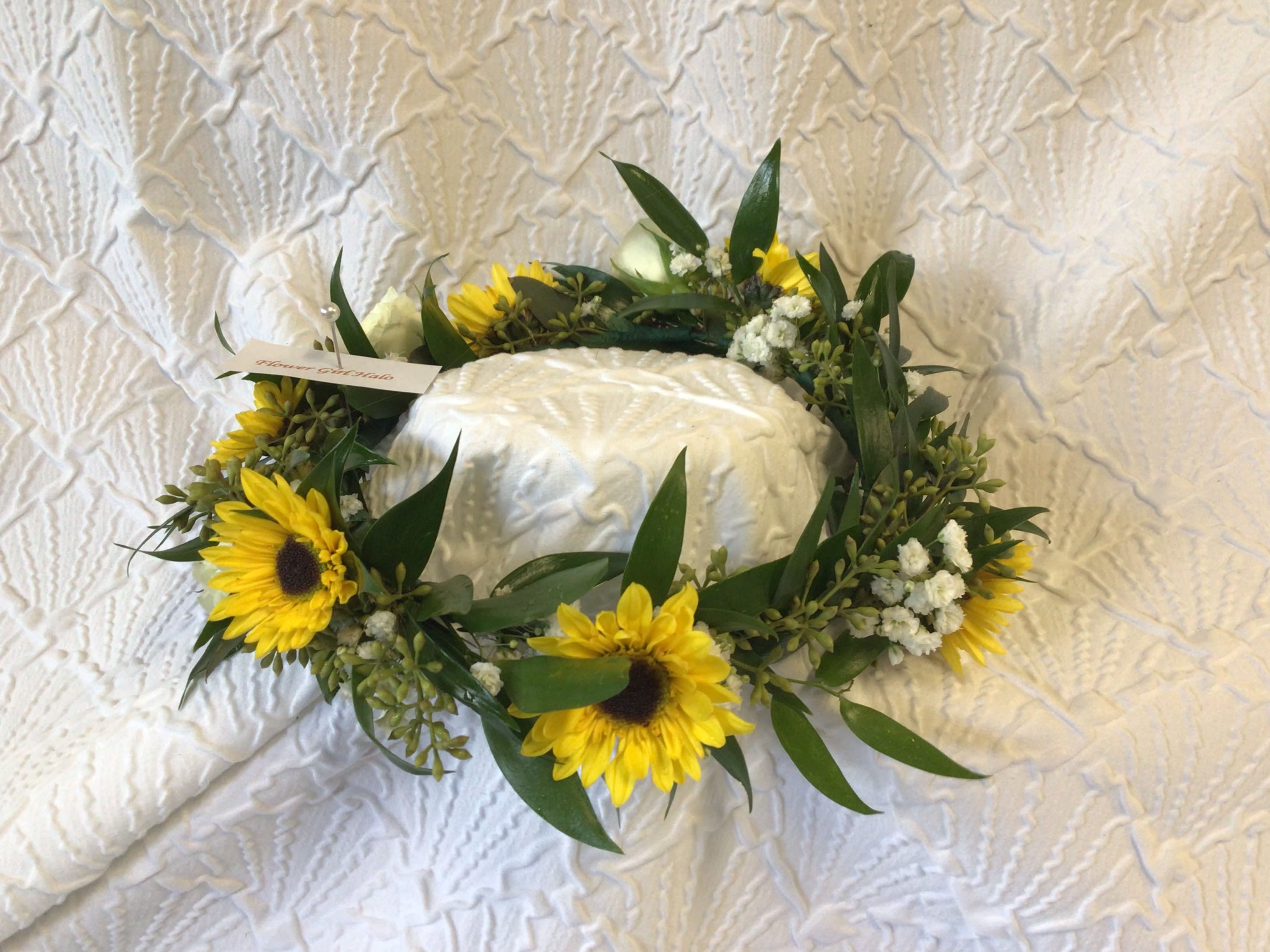 Sunflower wreath around a white cake on a textured cloth