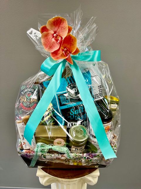 Gift basket wrapped in clear cellophane with a turquoise ribbon and orchid topper