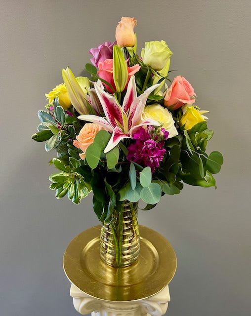 Mixed bouquet of roses and lilies in a gold vase