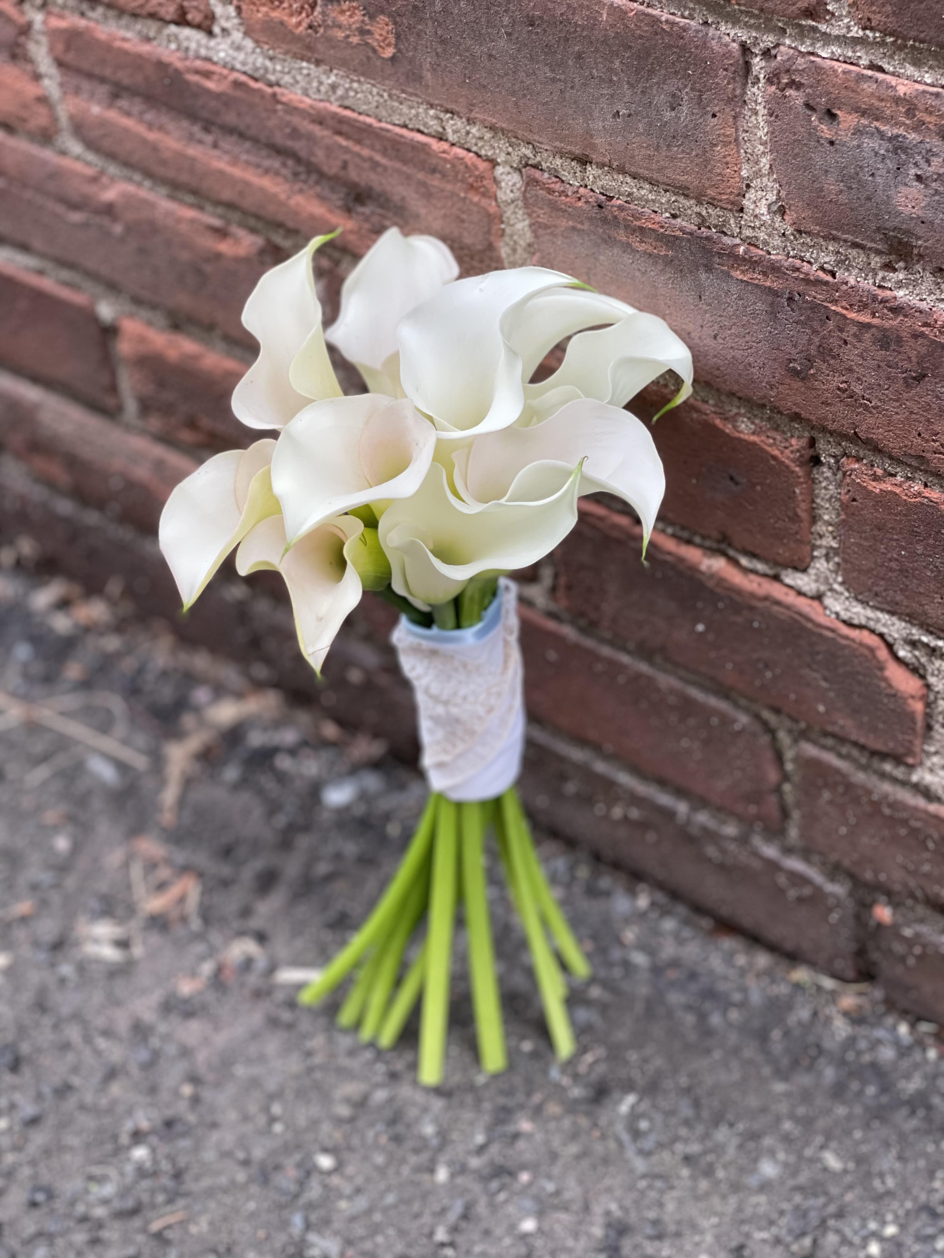 Small bouquet of white calla lilies tied with white ribbon