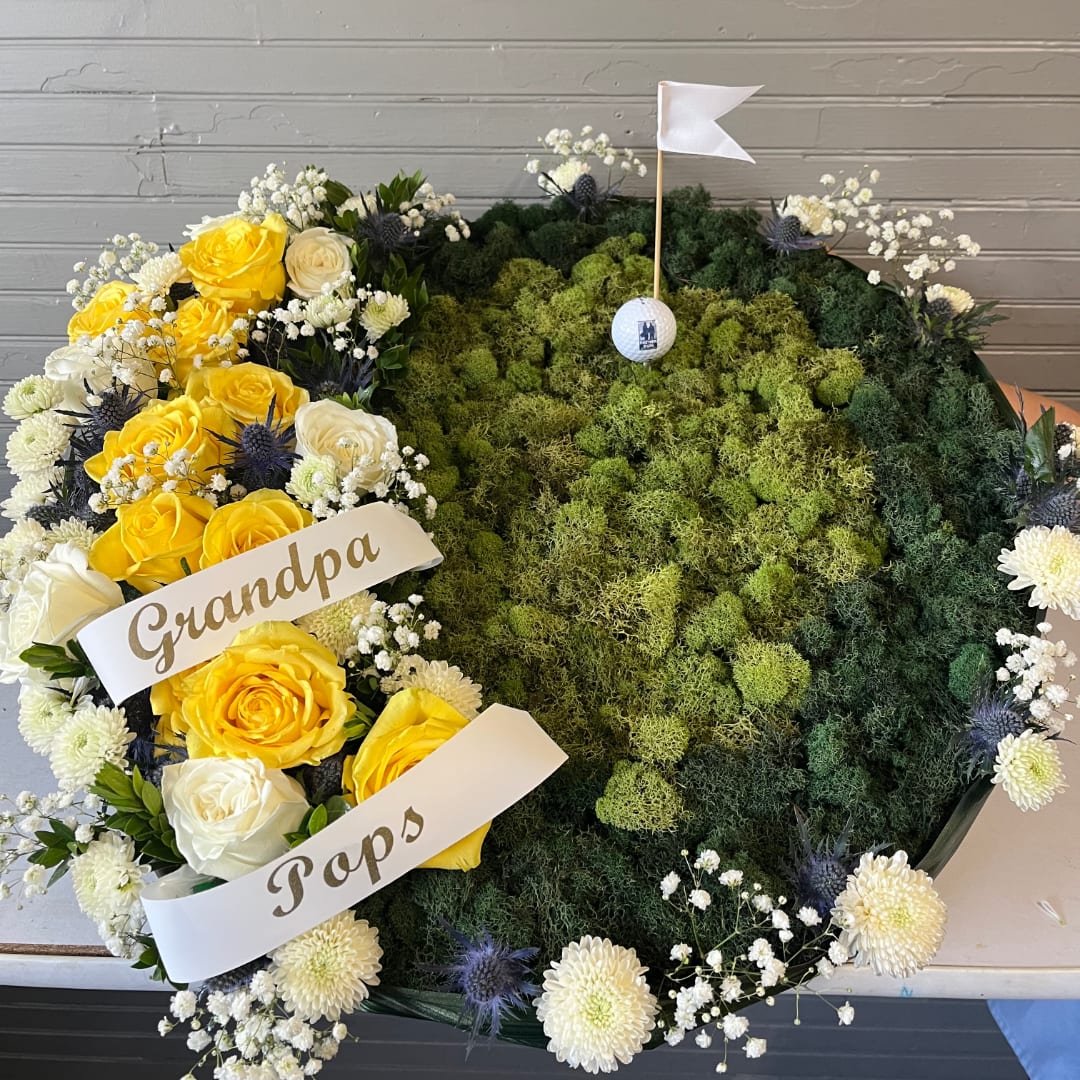 Heart-shaped floral tribute with yellow and white roses and a golf-themed center