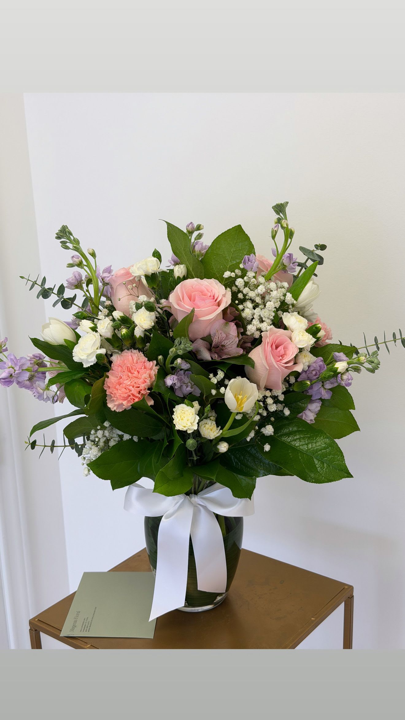 Pink and white mixed bouquet in a glass vase with a white ribbon
